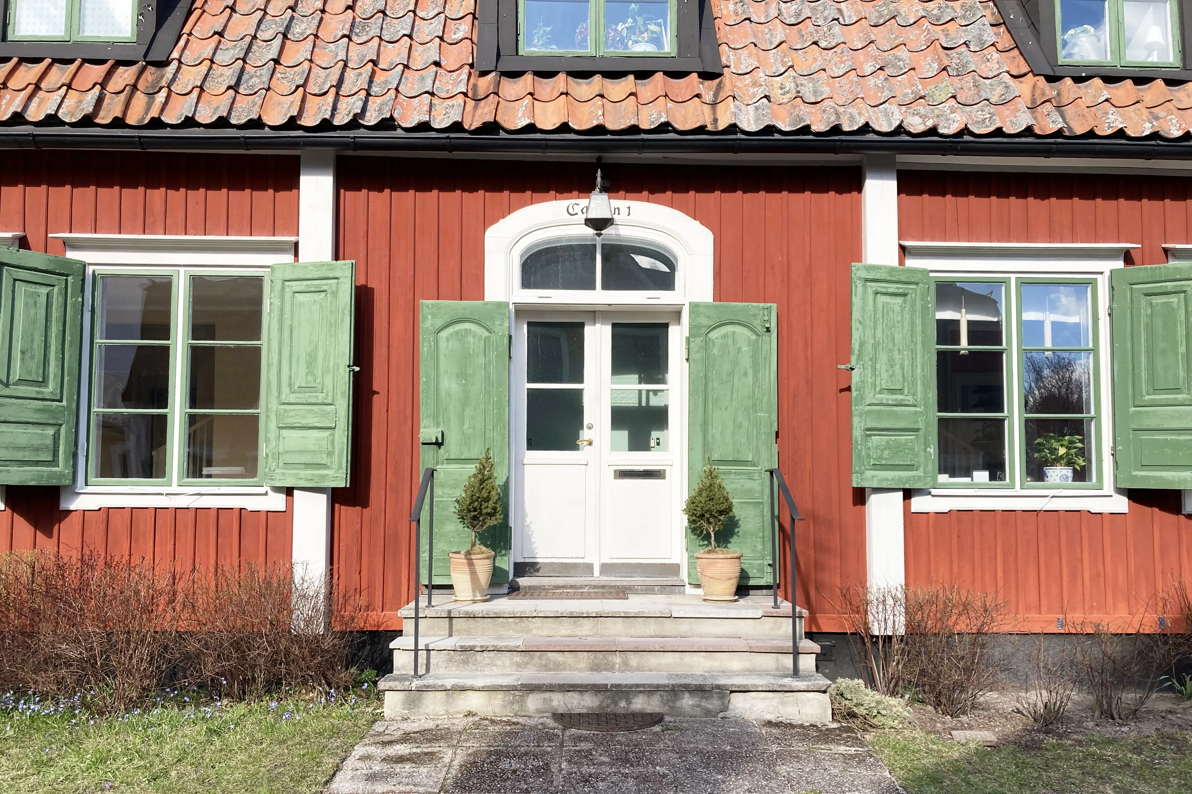 Kanton 1. Rött hus med gröna fönsterluckor. Tegeltaket har tak-kupor.