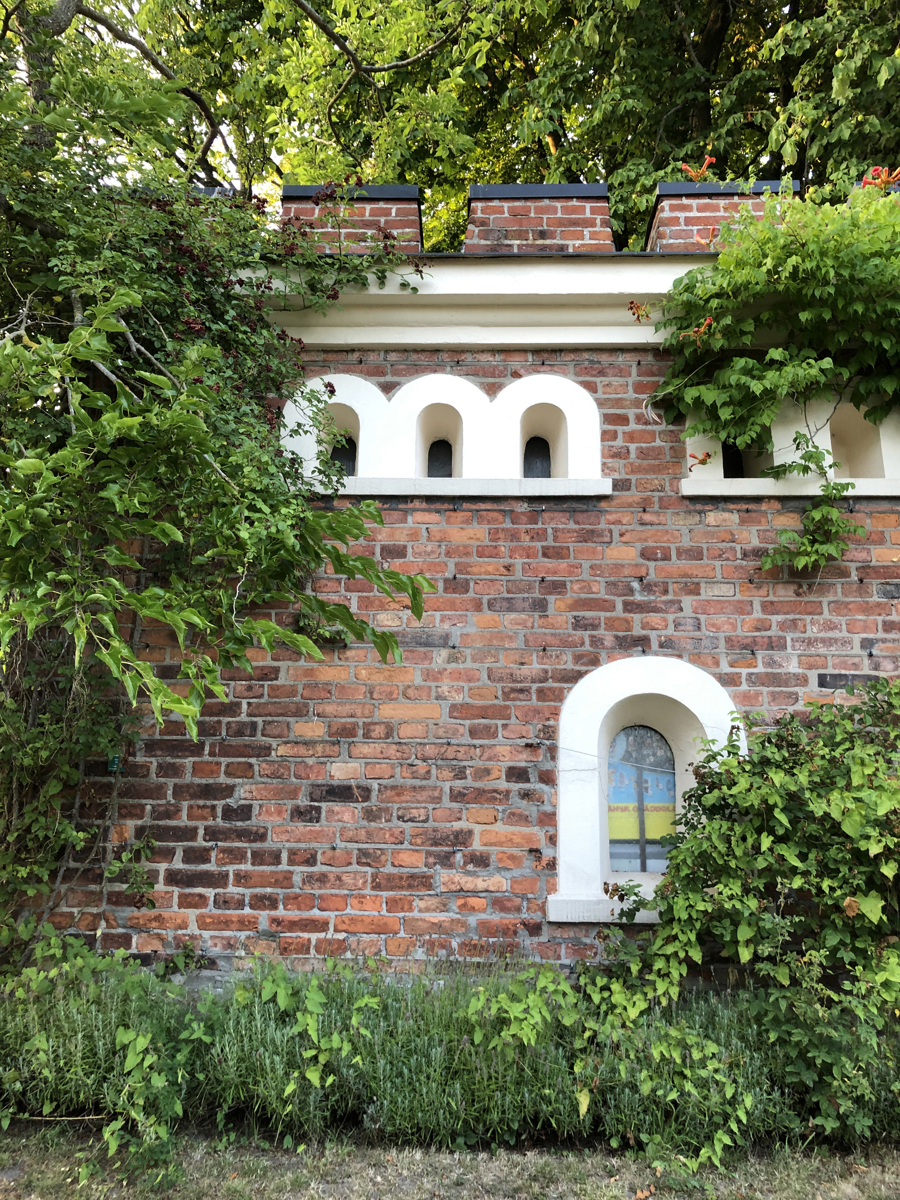 Kolhusets tegelvägg med grönska omkring