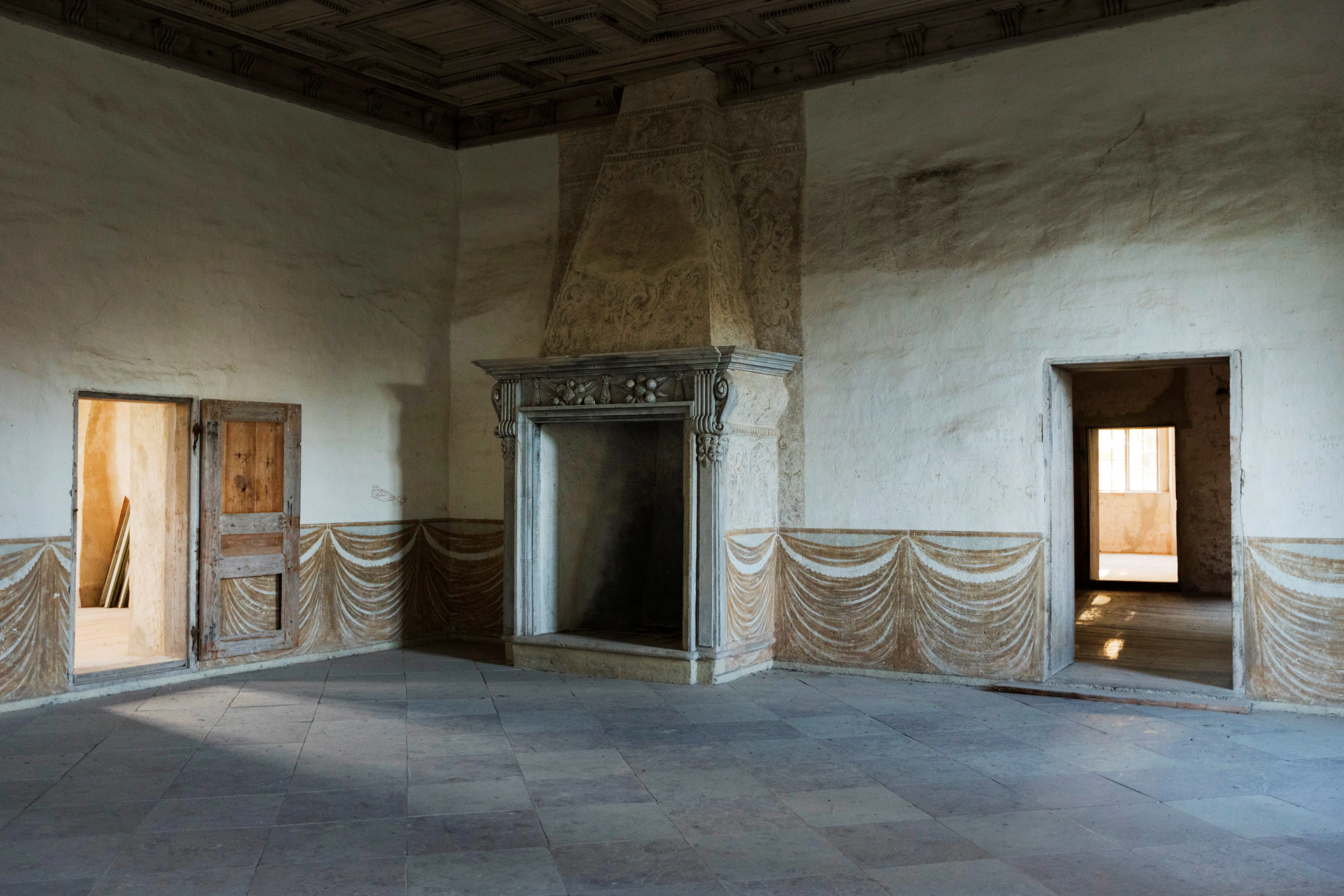 Interiör, Tynnelsö slott. Sal med stengolv och en stor eldstad med stendekor. Väggarna har målningar som föreställer draperat tyg.