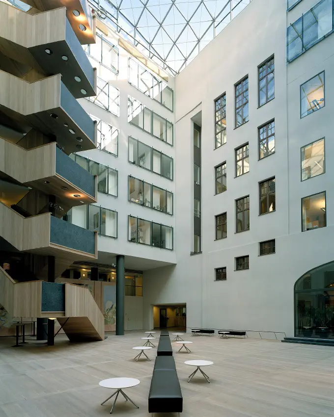 Glastäckt atrium-gård i kvarteret Tigern, som omges av modernistiska fasader med stora fönsterytor.