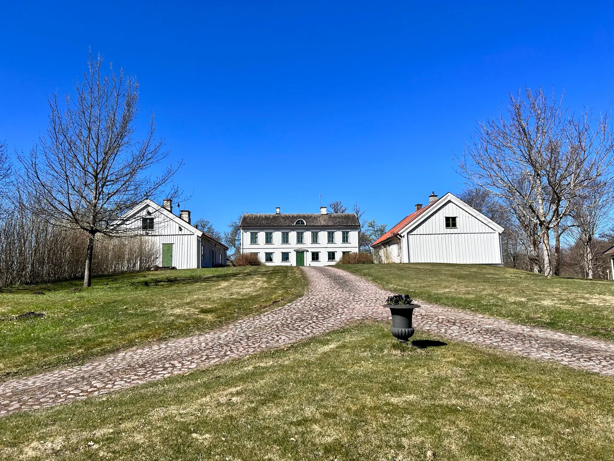 Höjentorp. Den två våningar höga huvudbyggnaden och de två flyglarna är alla klädda i vitt trä och nås via en stenlagd väg.