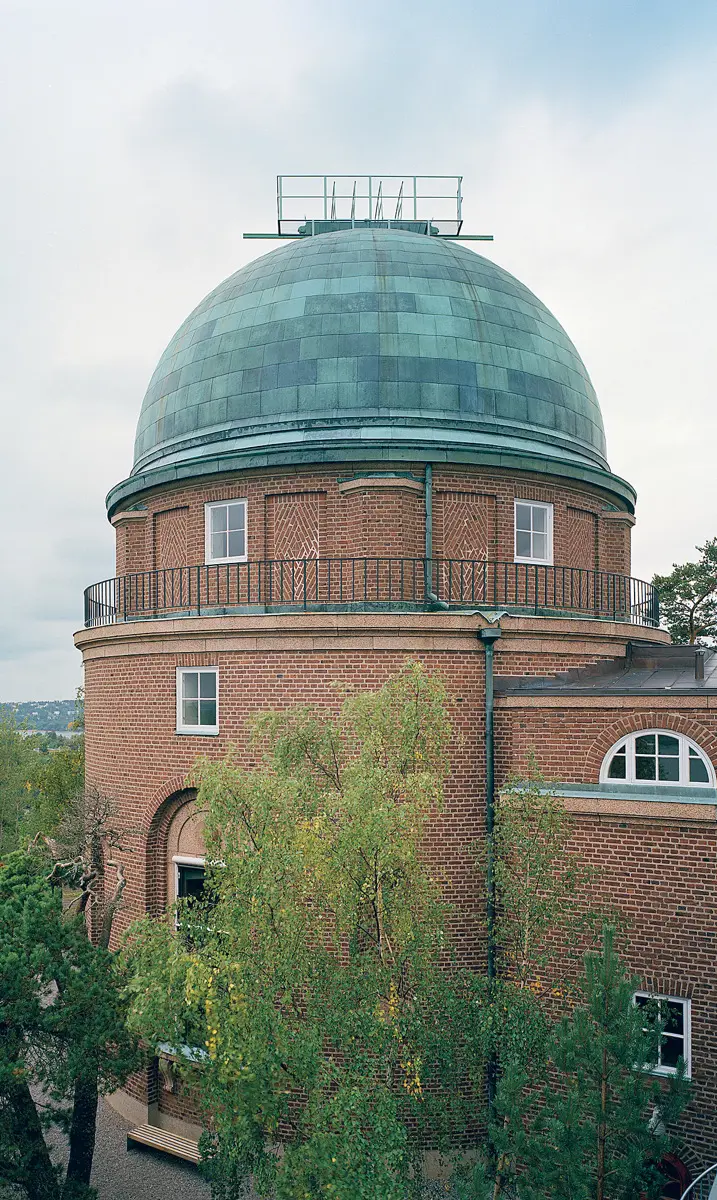Stockholms observatorium. En tegelbyggnad med ett runt torn som har en kupol av ärgad koppar.