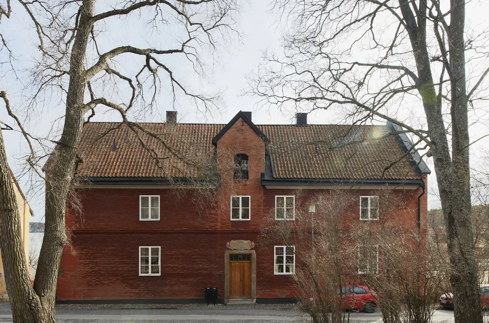 Ett hus med rödputsad fasad och två träd i förgrunden.