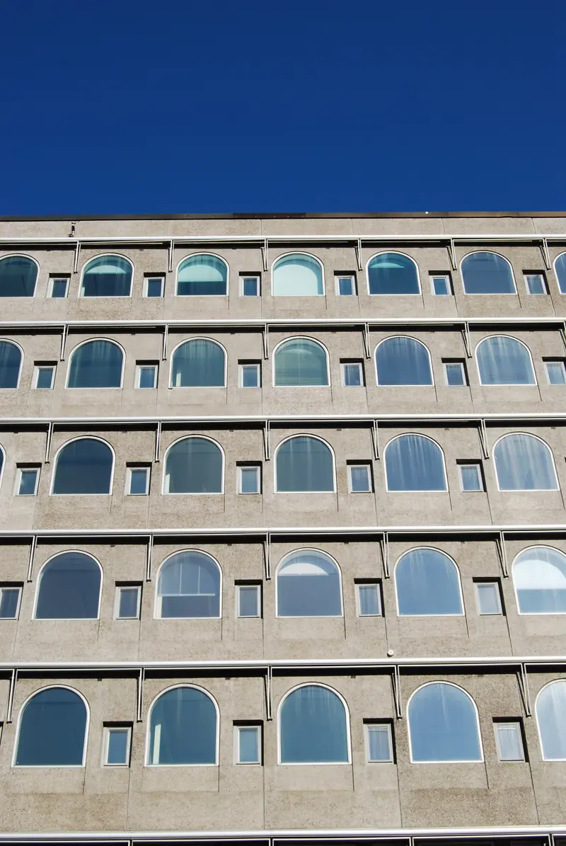 Fasad av betongelement med rundbågade fönster.