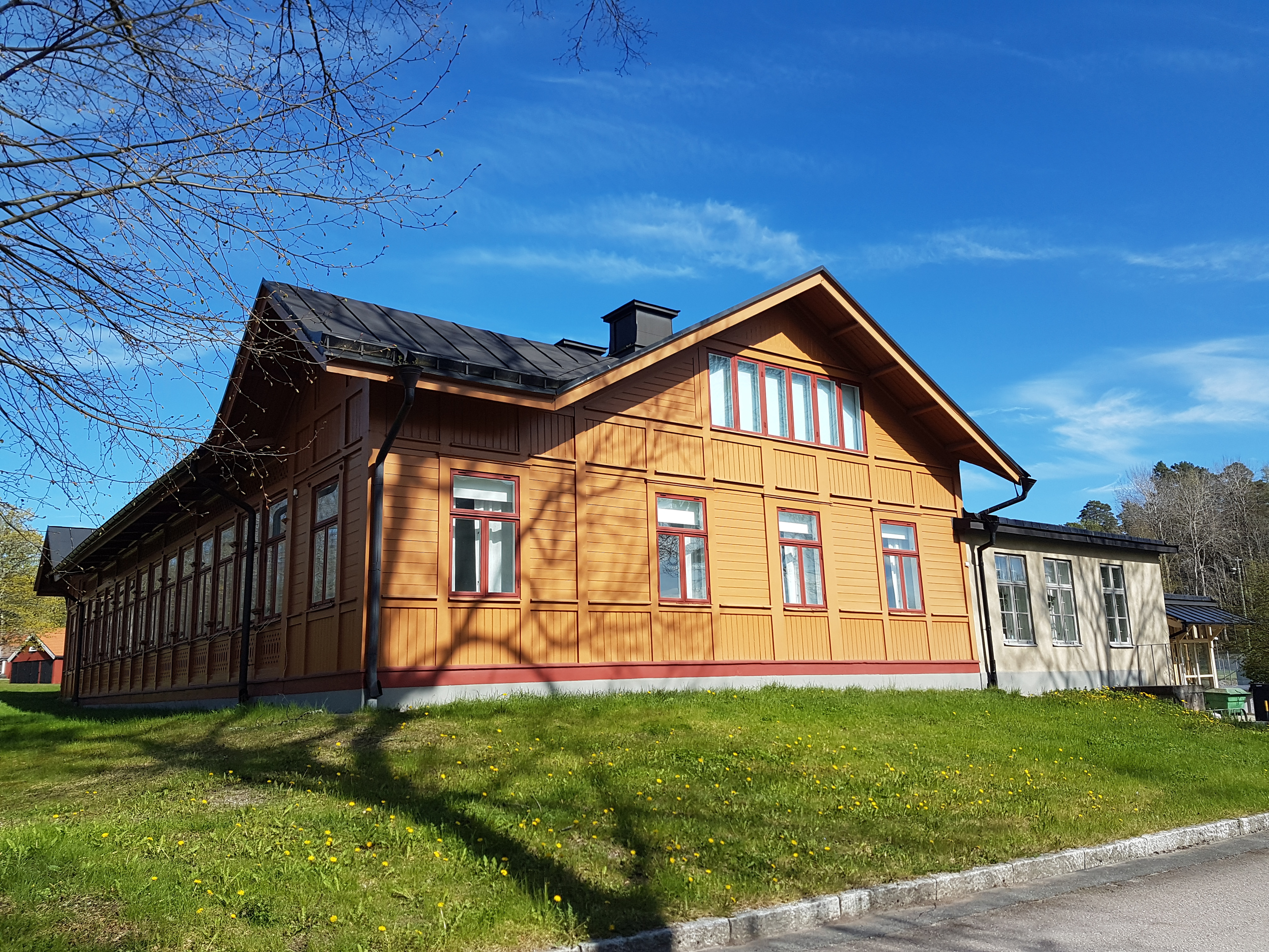 Rosersbergs kungsgård. Personalmäss uppförd för infanteri-skjutskolan. Låg, gul träbyggnad. Vår och grönska.
