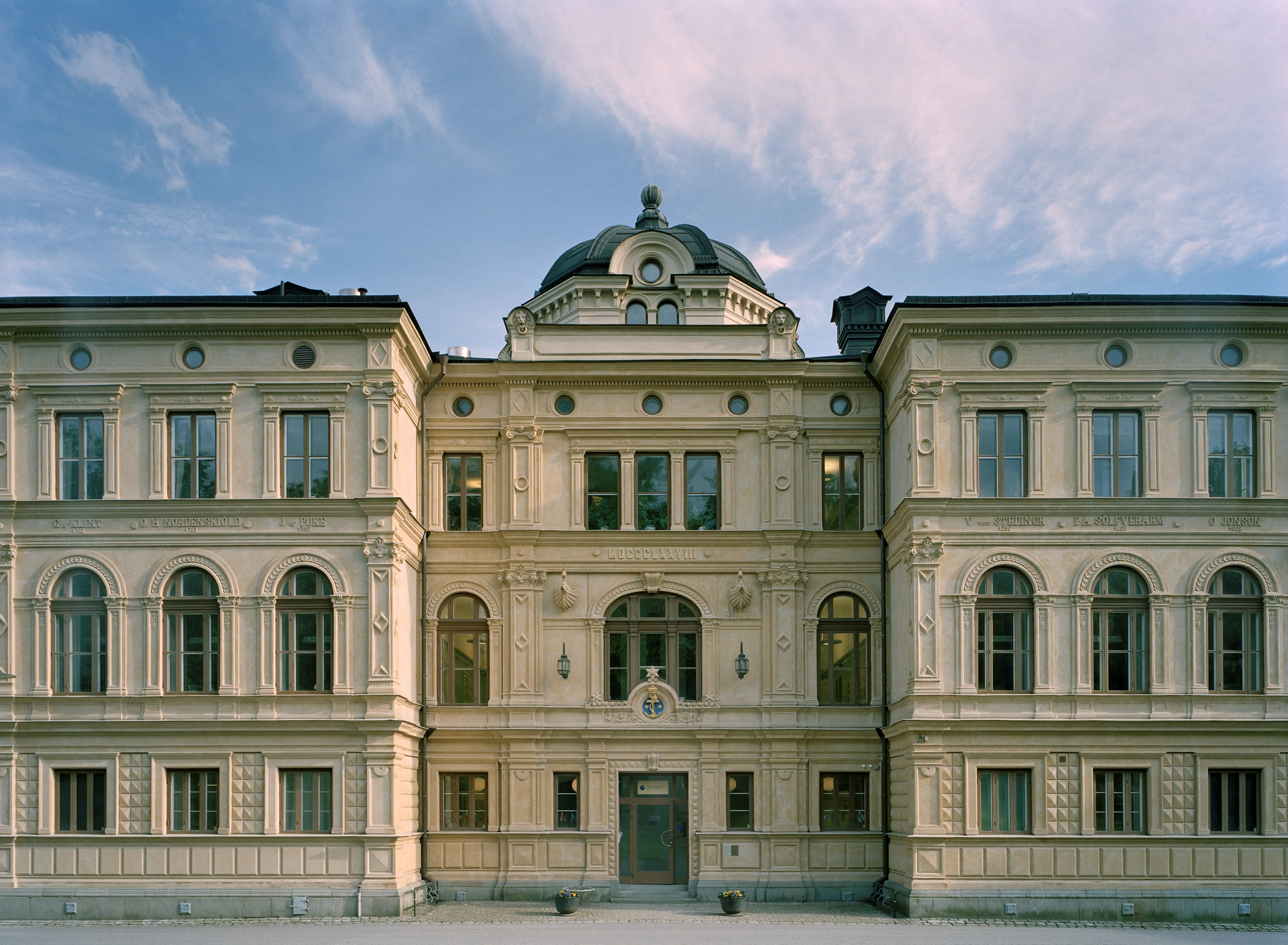 Gamla sjökrigs-skolan på Skeppsholmen. En pampig trevåningsbyggnad med kopparklädd tak-kupol. Fasaden har nationalromantisk dekor.