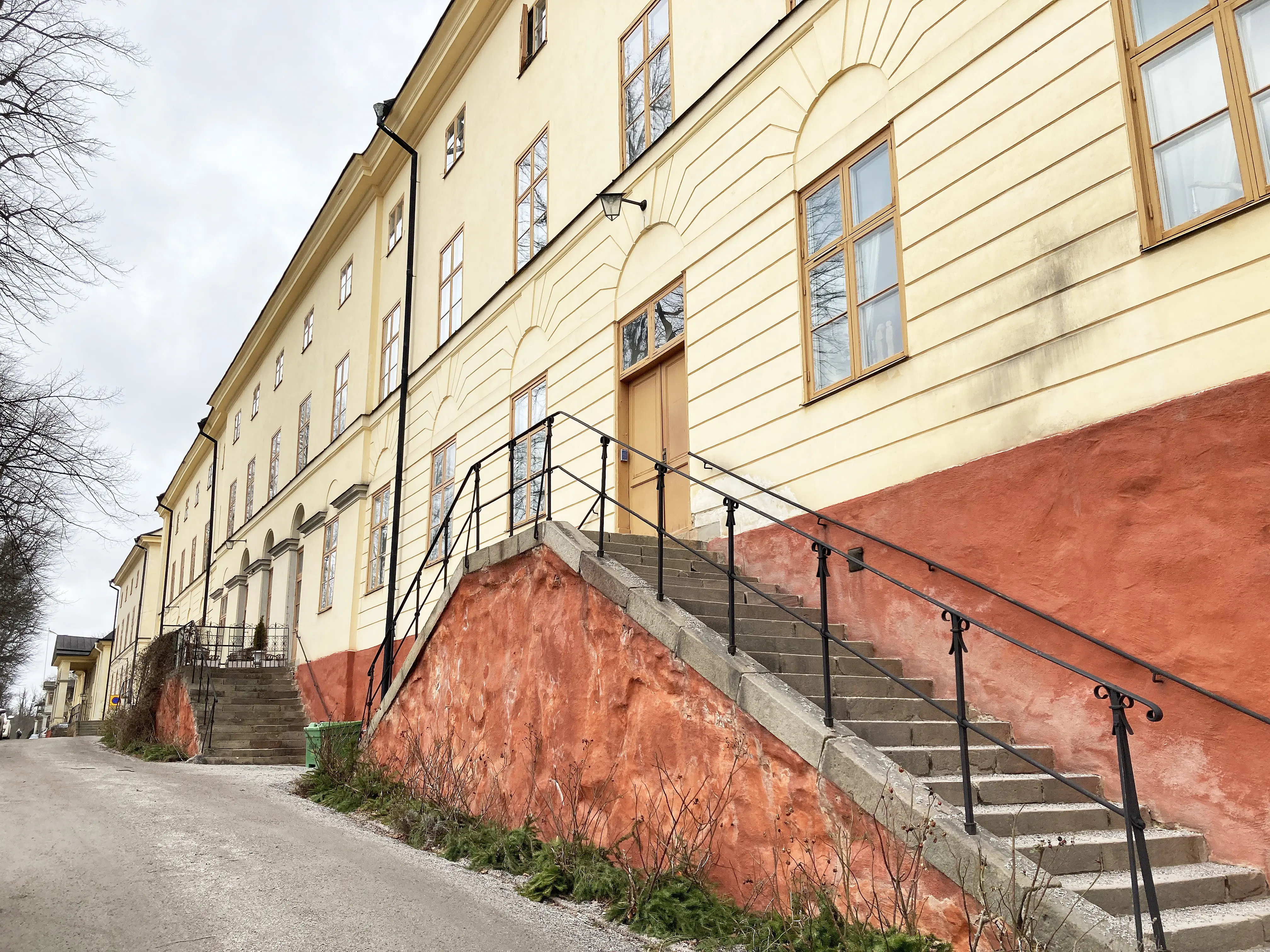 Kavaljershuset på Malmen vid Drottningholm. Lång, gulputsad trevåningsbyggnad i klassicistisk stil, med röd sockel.