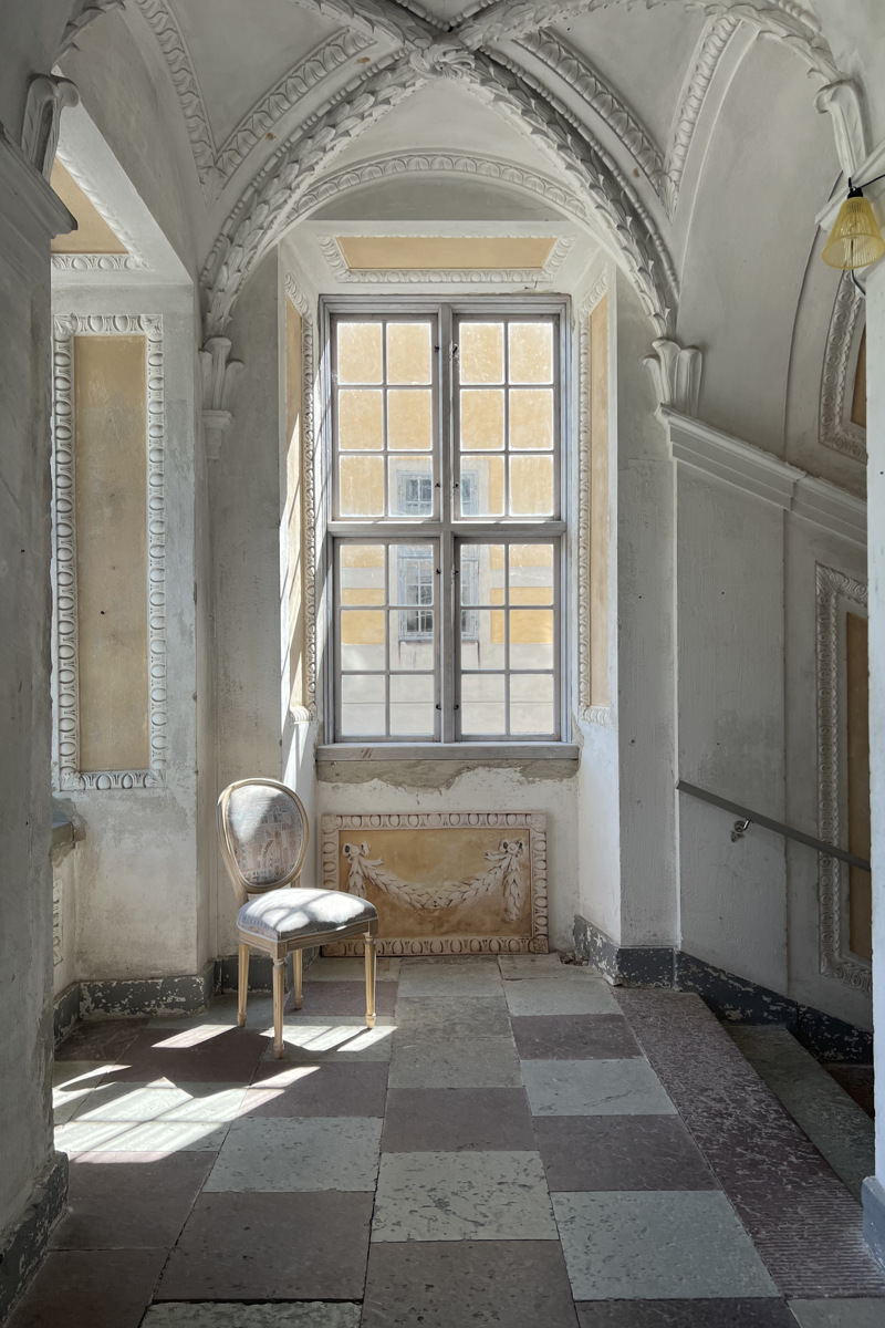 Interiörbild som visar ett fönster, stengolv och valvtak. 