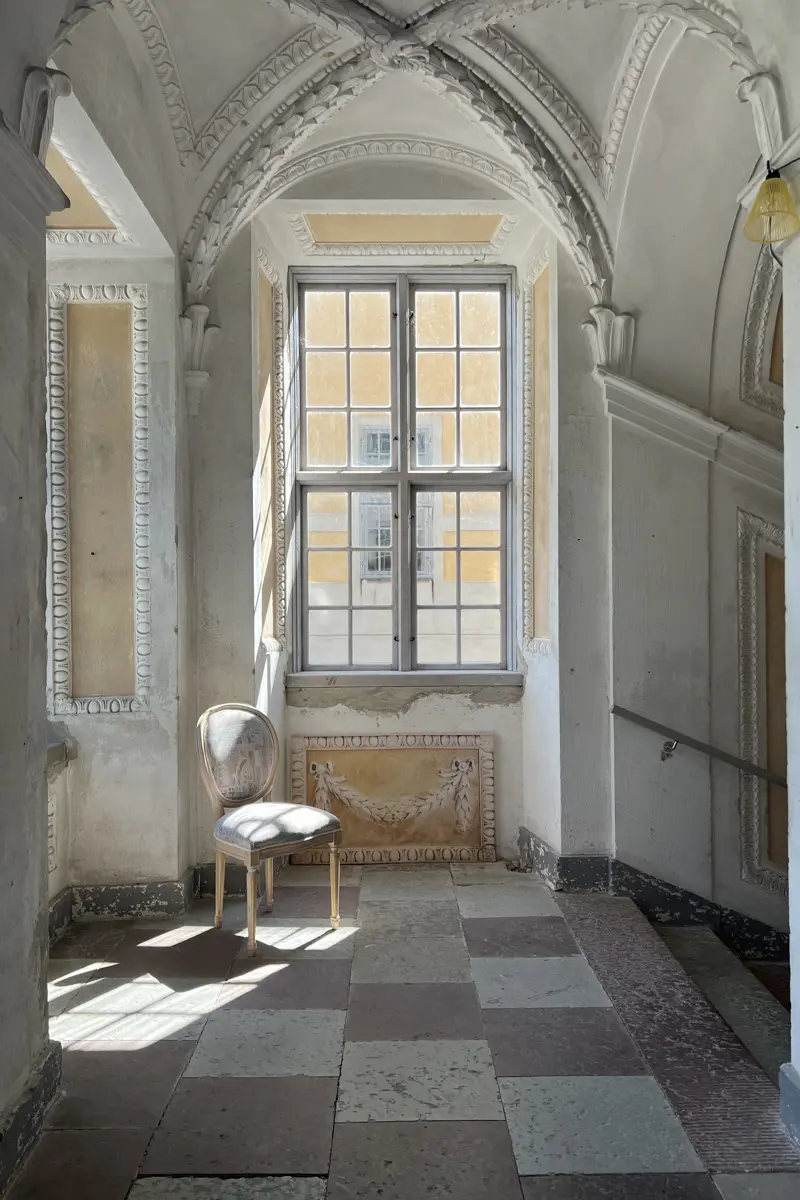 Interiörbild som visar ett fönster, stengolv och valvtak.