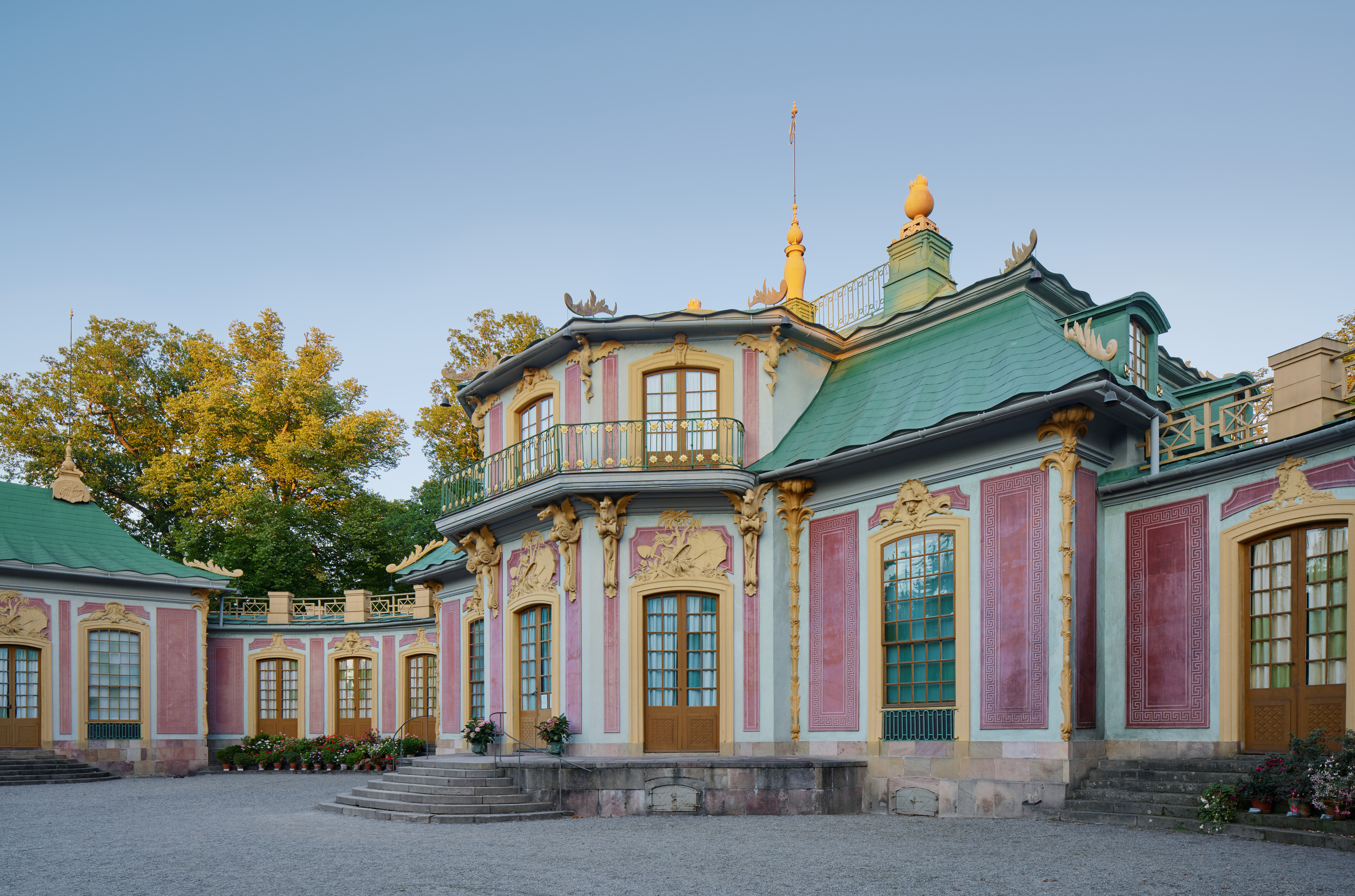 Kina slott, Drottningholm. Litet rött rokoko-slott med svängda flyglar och grönt plåt-tak. Tak och fasad har skulpterad, gul dekor.