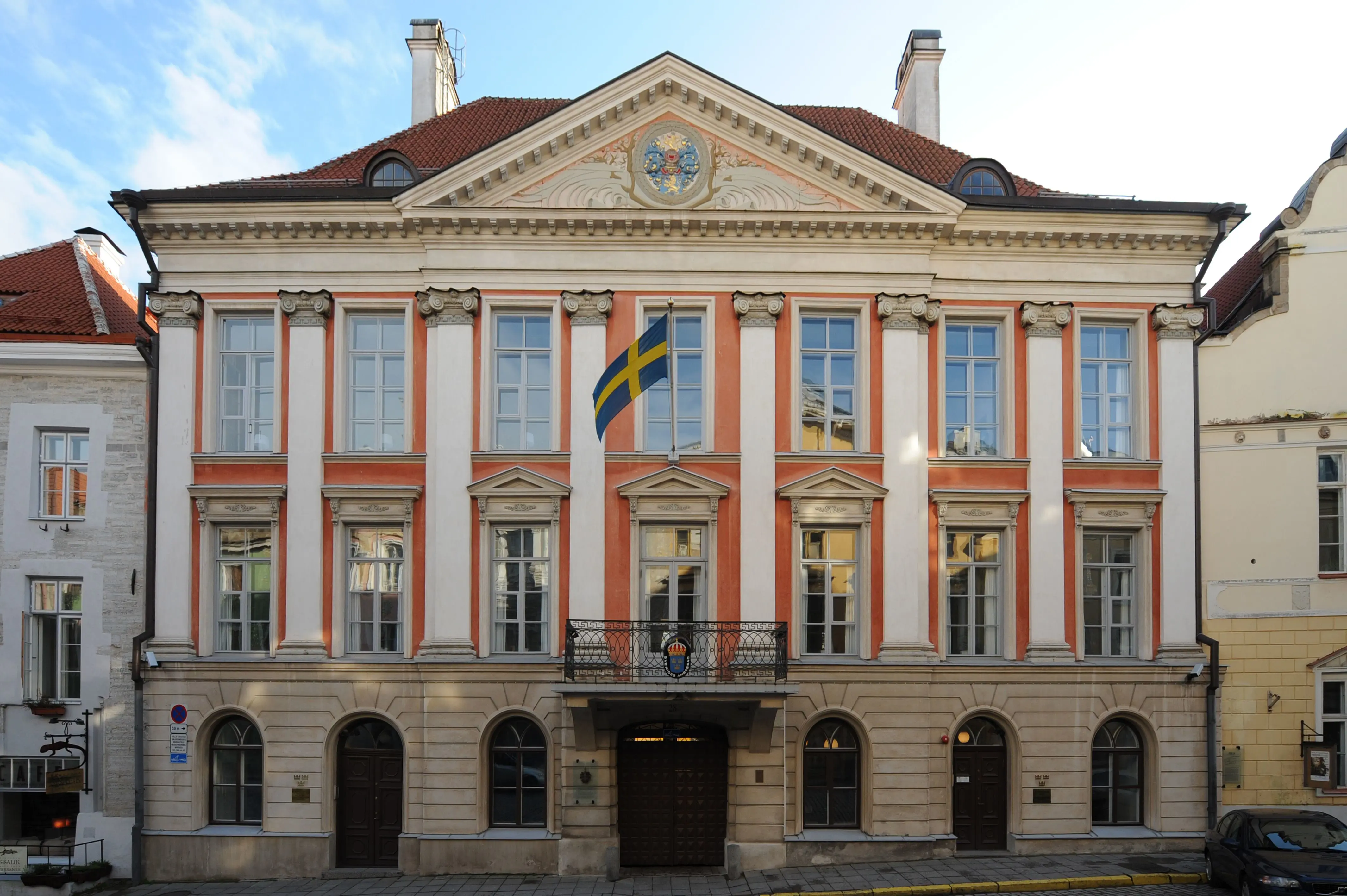 Ambassaden i Tallinn, fasad mot gatan. Trevåningsbyggnad i röd puts, med stensockel, vita pilastrar och en stor praktgavel.