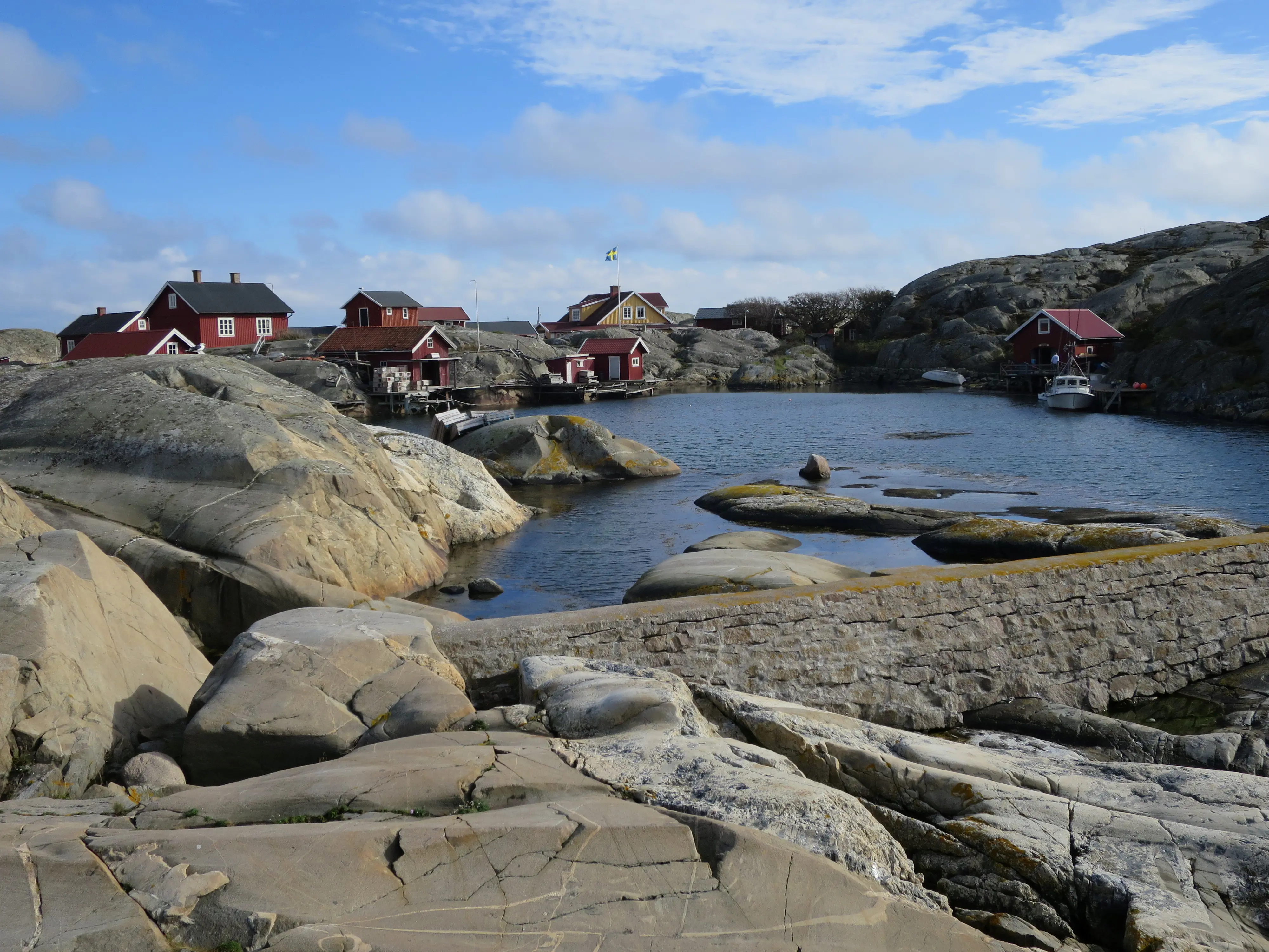 Bebyggelse runt en naturhamn på Väderöarna. Klipporna runt hamnen är rundade av vågorna.