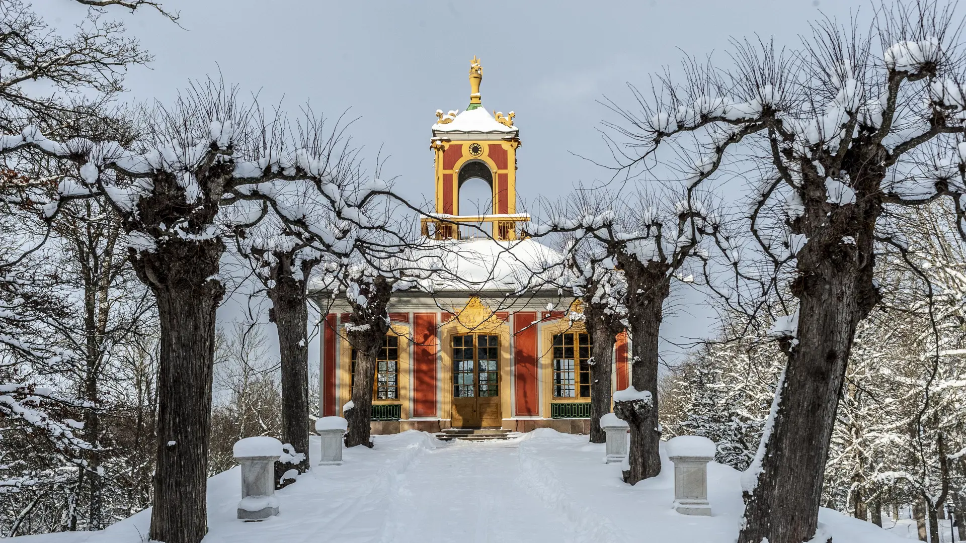 Confidensen vid Kina slott, Drottningholm. Röd paviljong med gula snickerier och ett torn. Vinter och snö.
