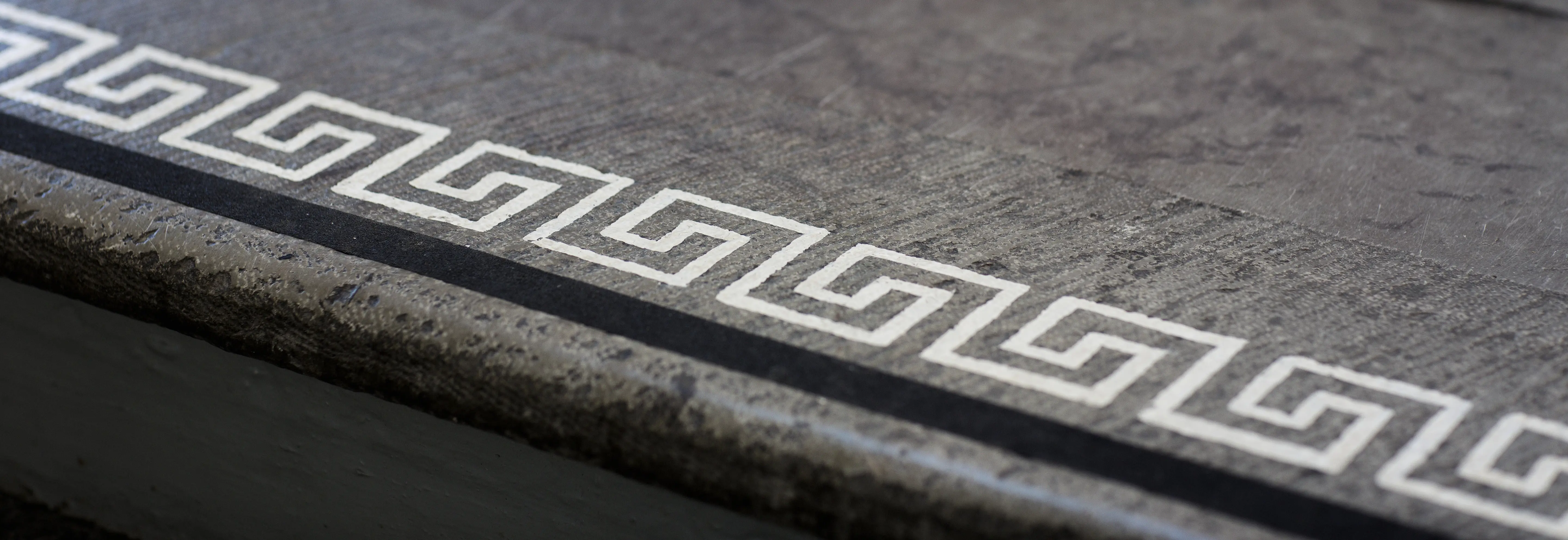 Närbild på ett trappsteg av sten. Kanten har en vit meander-slinga som tillgänglighets-anpassning.