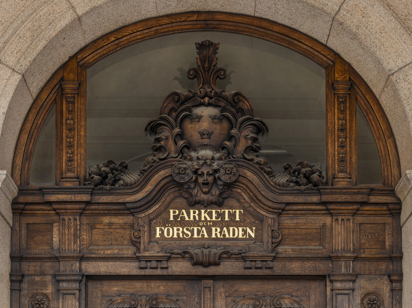 Träsniderier i en av Operans portar. En text i guld säger "parkett och första raden".