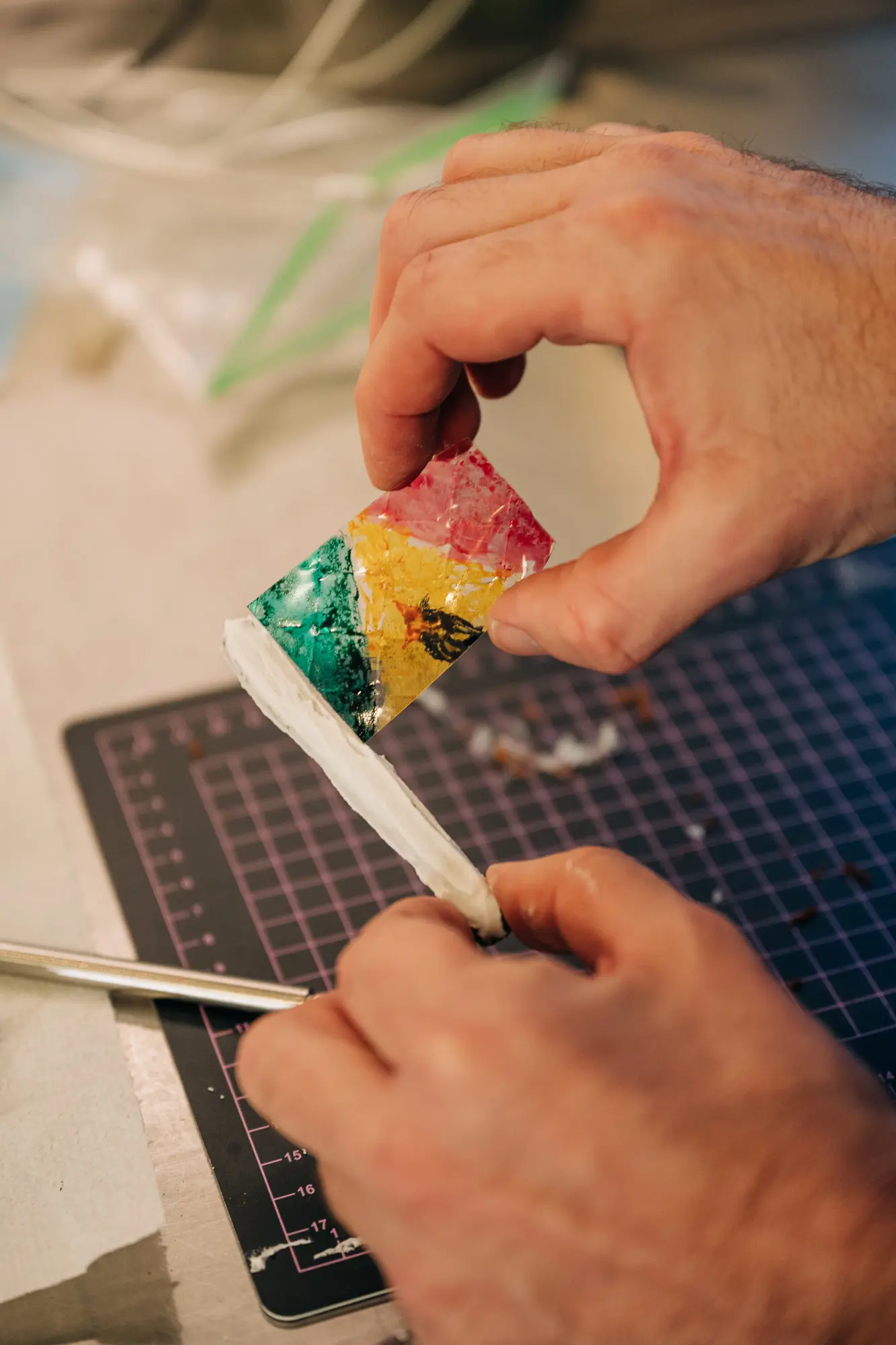 Ett par händer håller i en liten egengjord flagga, gjord av gelatinblad och karamellfärg. Flaggan är grön, gul och röd.