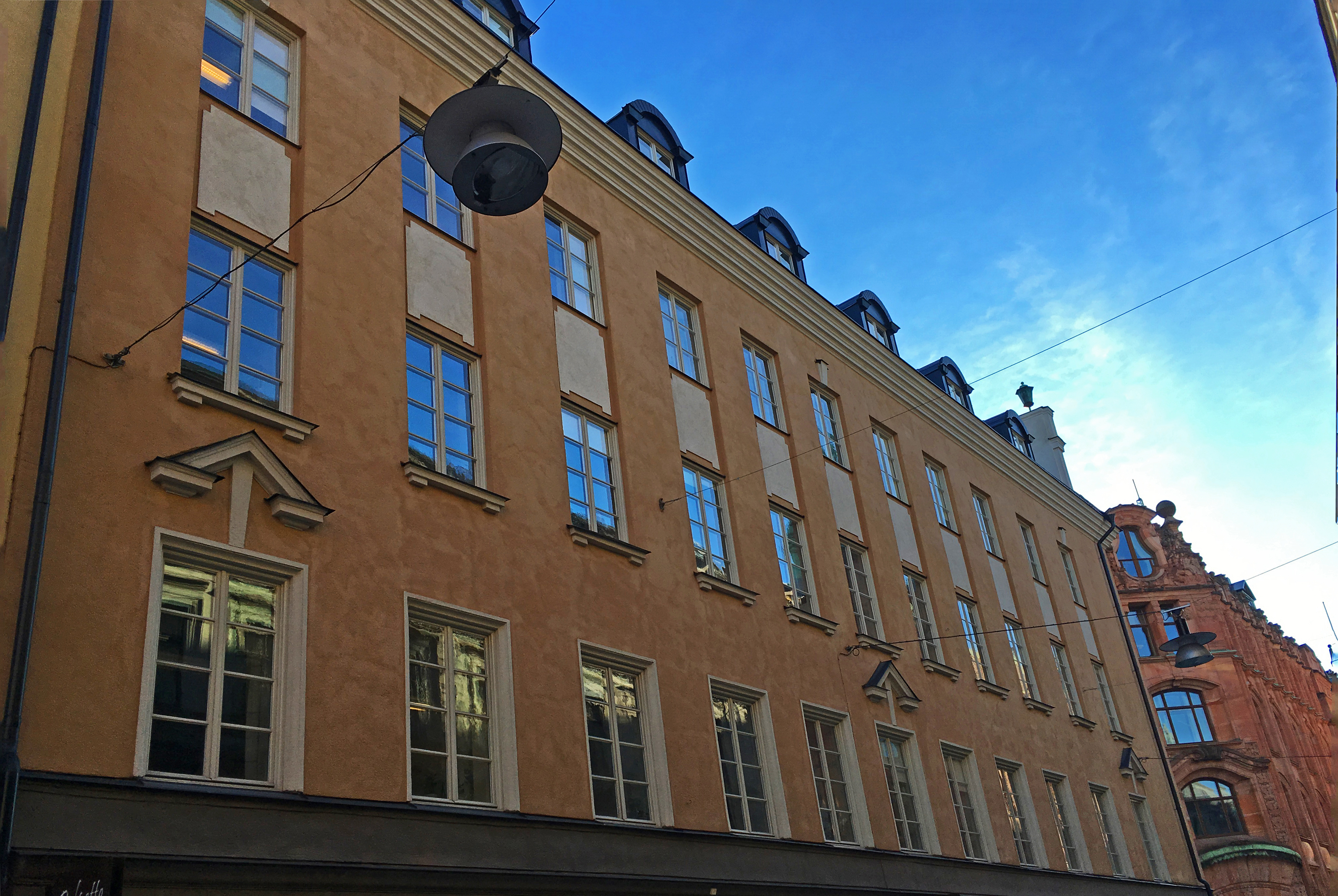 Drottninggatan 6. Beige-putsad byggnad i fyra våningar, med tak-kupor och klassicistisk dekor.