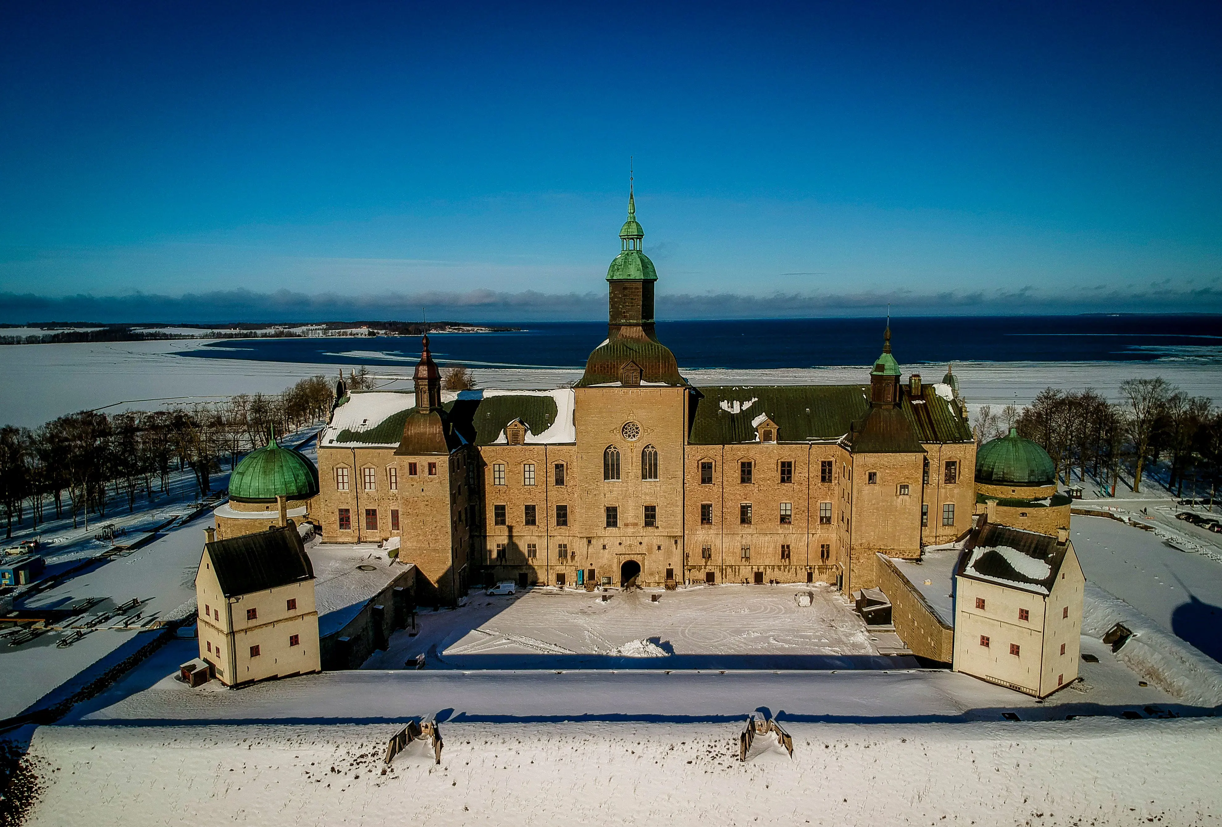 Vadstena slott med sina fem torn. I förgrunden vallen runt borg-gården, i bakgrunden Vättern. Vinter och snö.