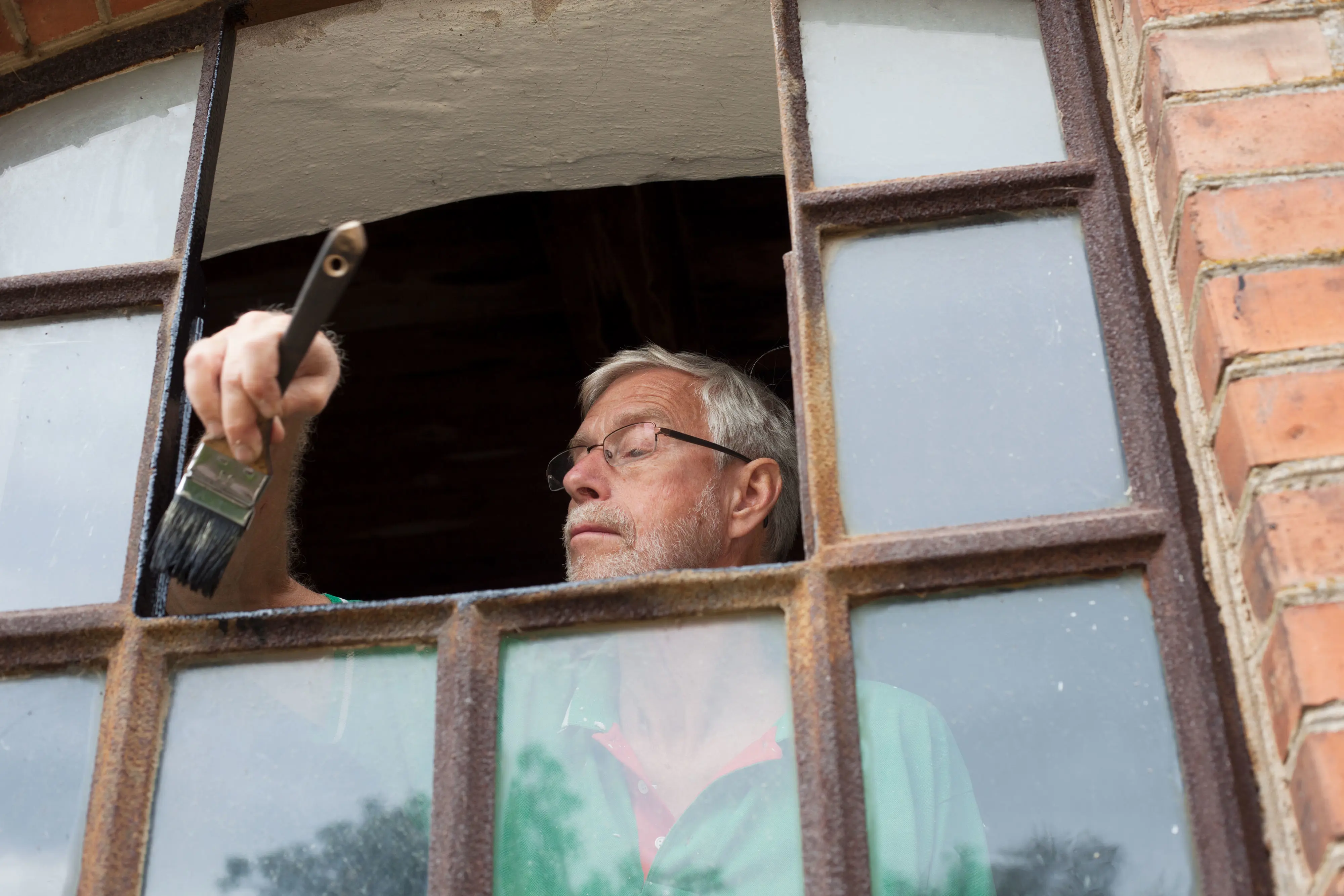Christer Erlandson målar järnfönster.