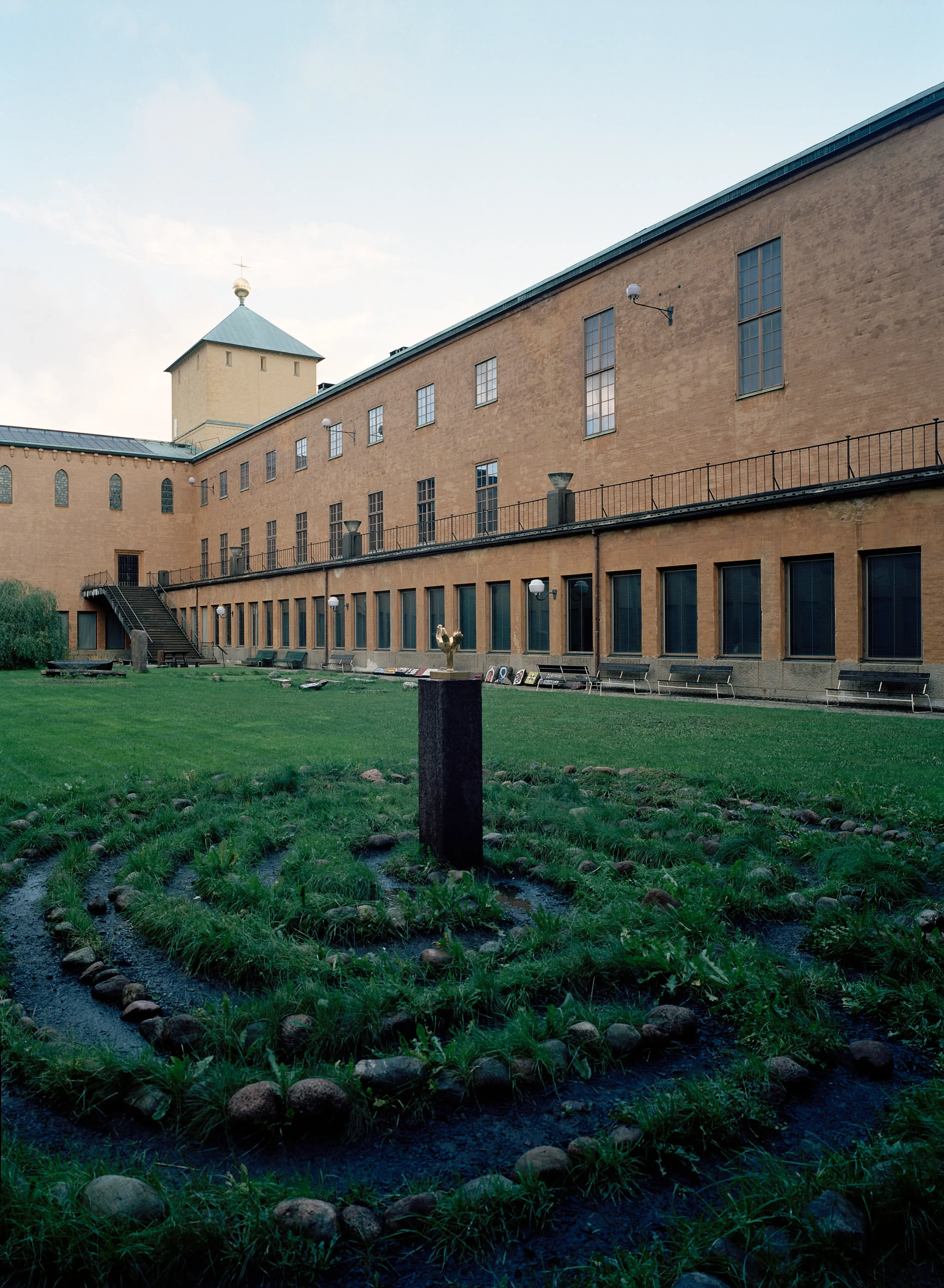 Innergården till historiska museet i Stockholm. En öppen gräsyta omgiven av strama husväggar.