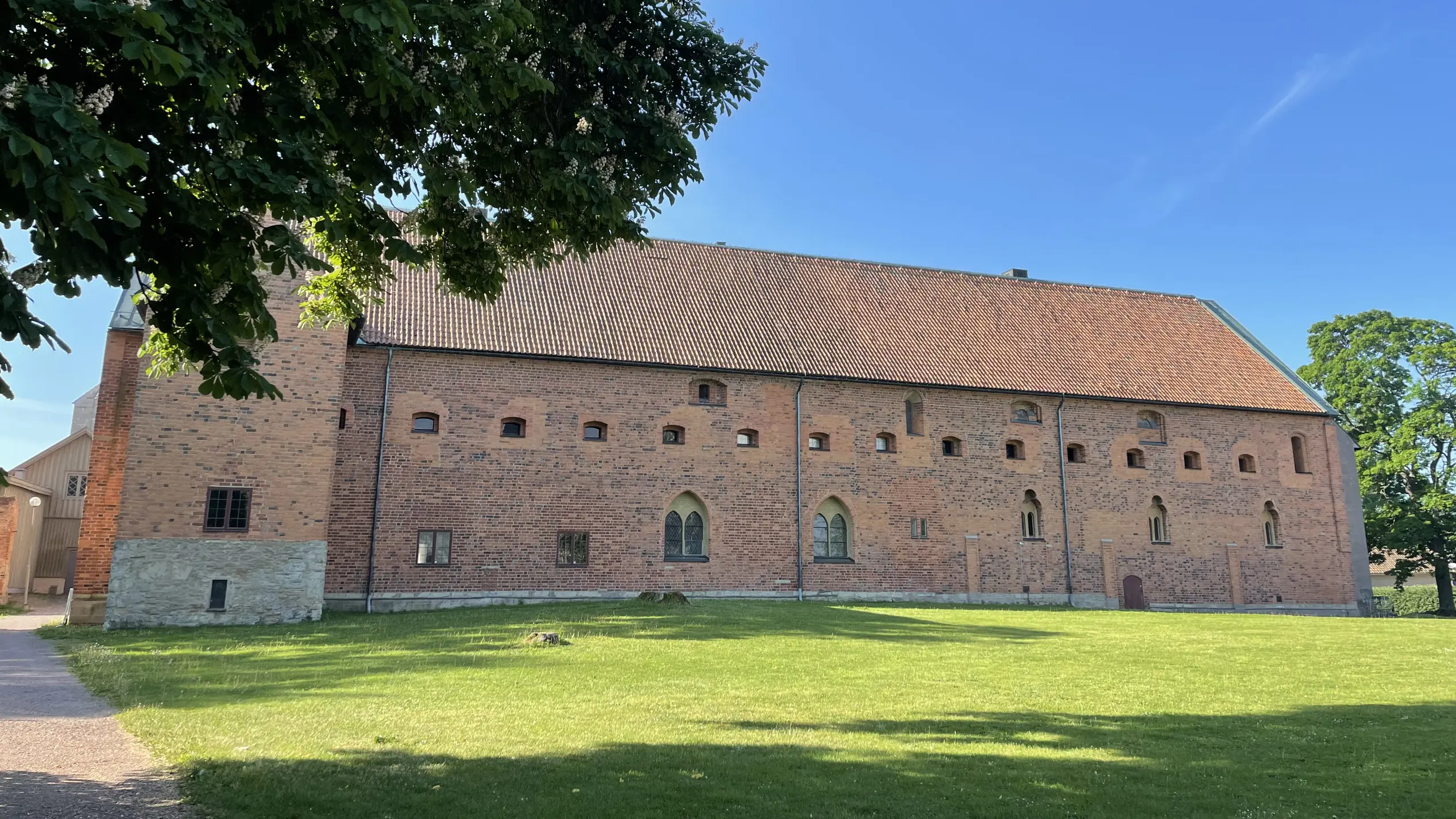 Nunneklostrets norra länga sedd från parken. Fasad och tak har rött tegel. Fönstren har tydlig medeltida stil.