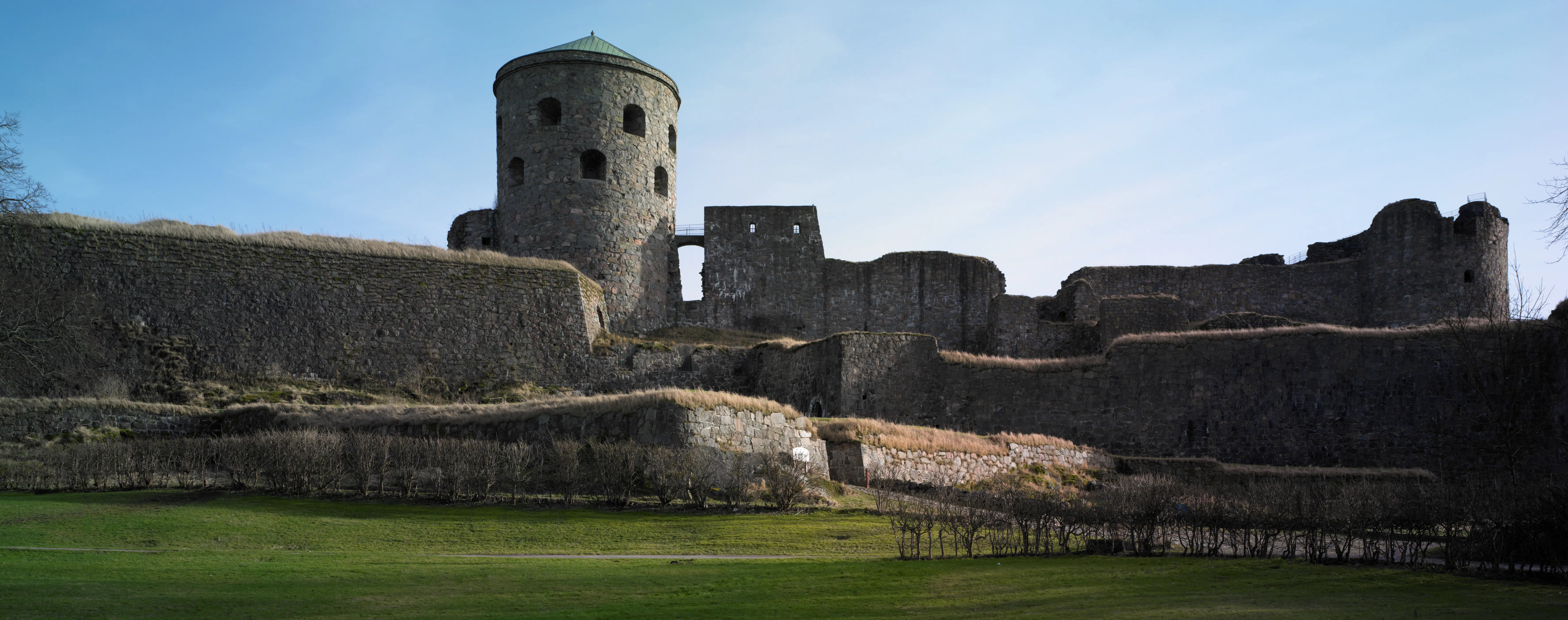 Bohus fästning, medeltida försvarsverk i sten. Ett runt torn är intakt, murarna är gräsbeväxta och delvis raserade.