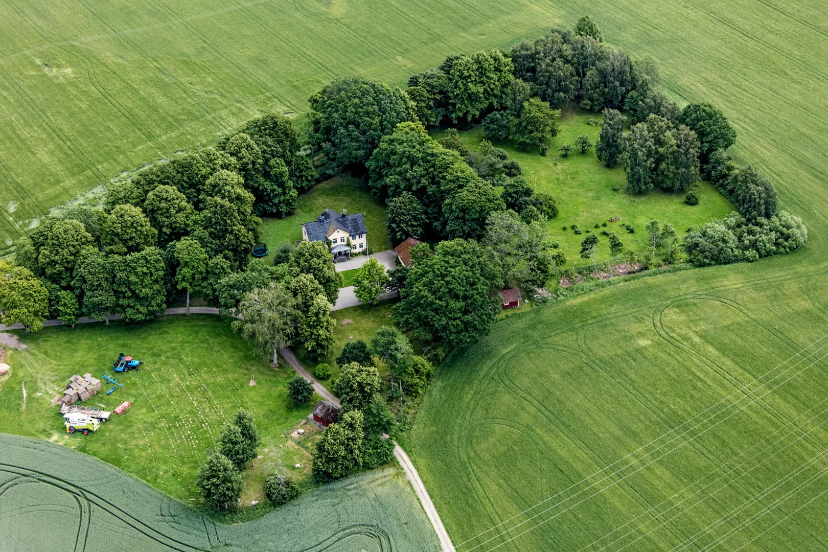 Flygbild av kungsladugården som omges av lövträd och gröna åkrar.