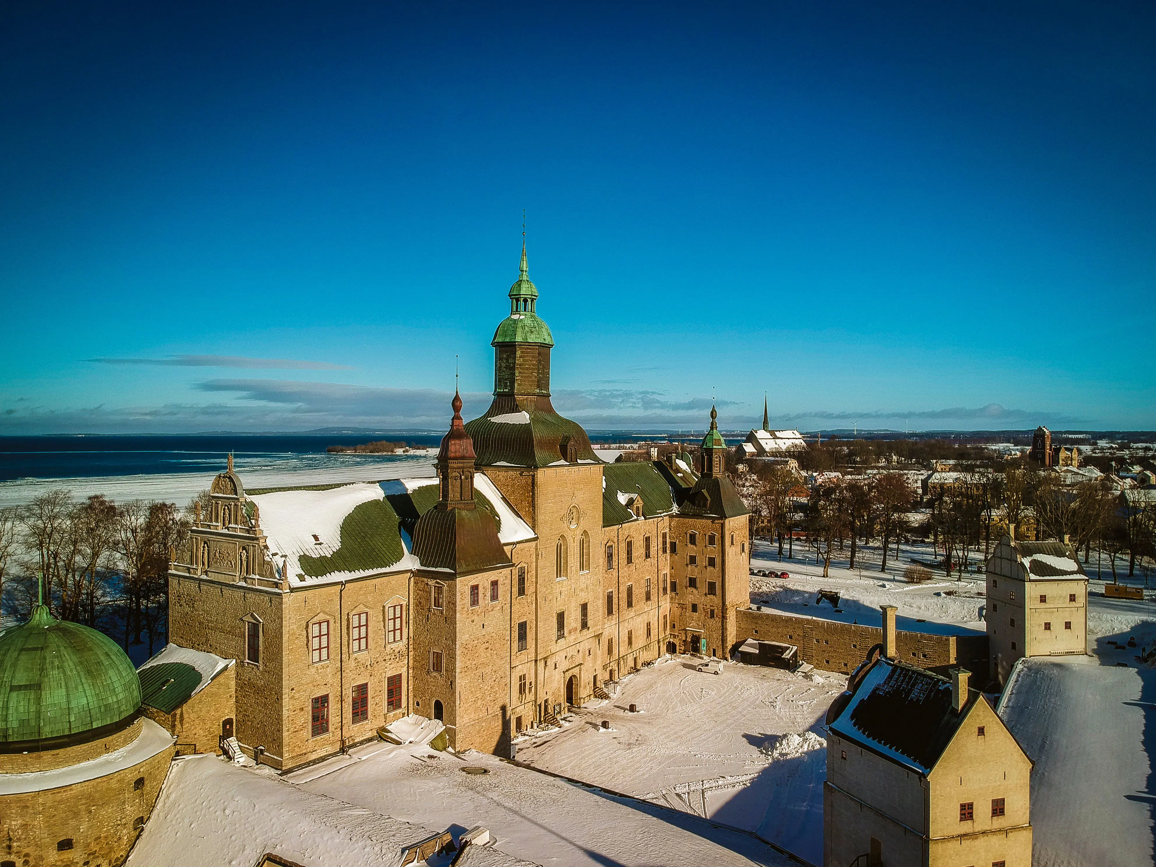 Vadstena slott med sina fem torn. I förgrunden vallen runt borg-gården, i bakgrunden Vättern och Vadstena kloster. Vinter och snö.