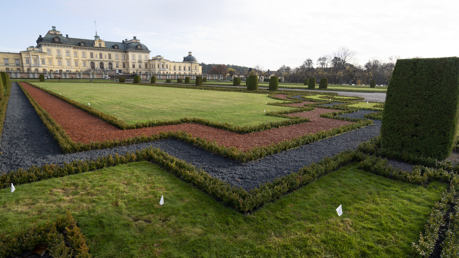 Framför Drottningholms slott avgränsas en gräsyta från en grusgång med smala strängar av buxbom.