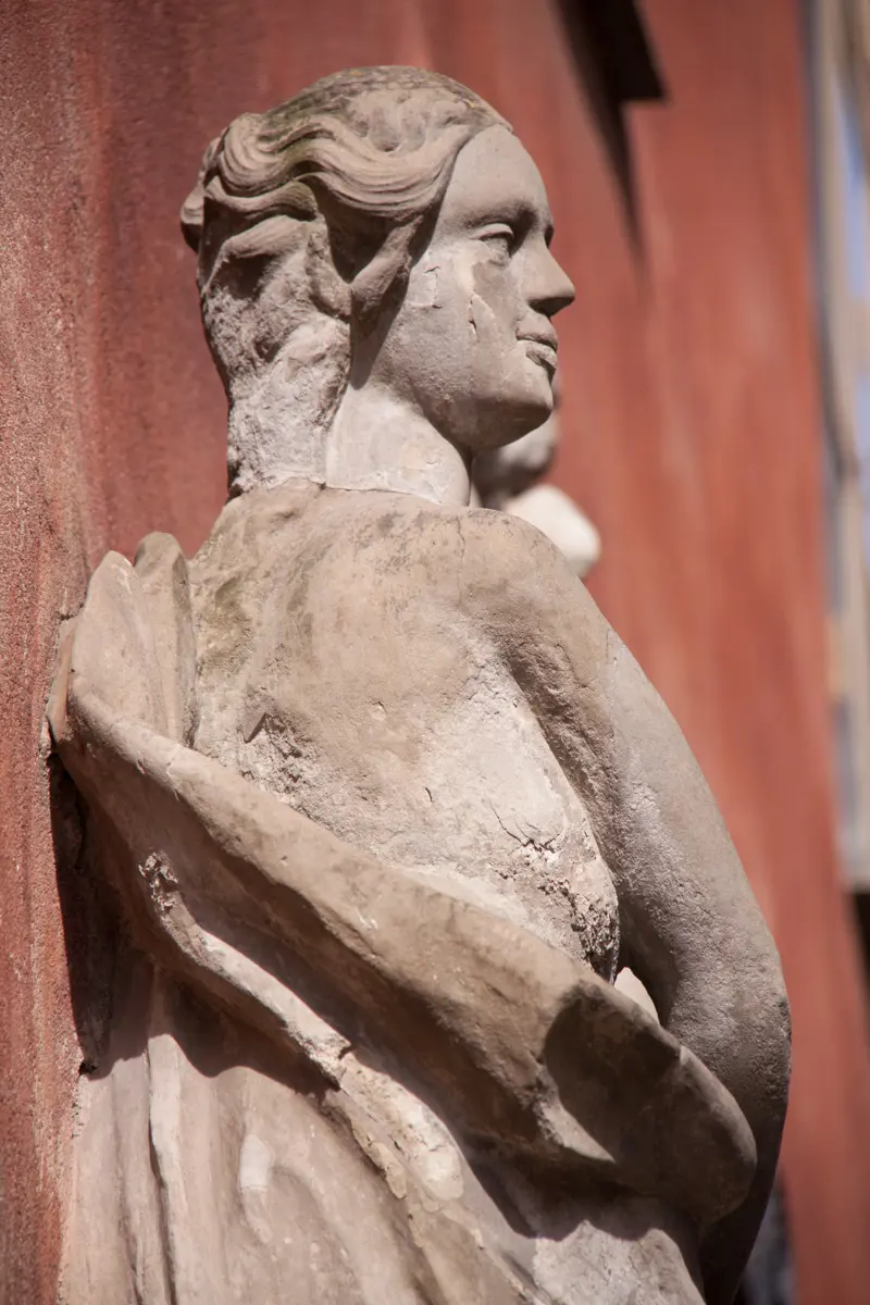 Skulptur av en kvinna på den röda fasaden.