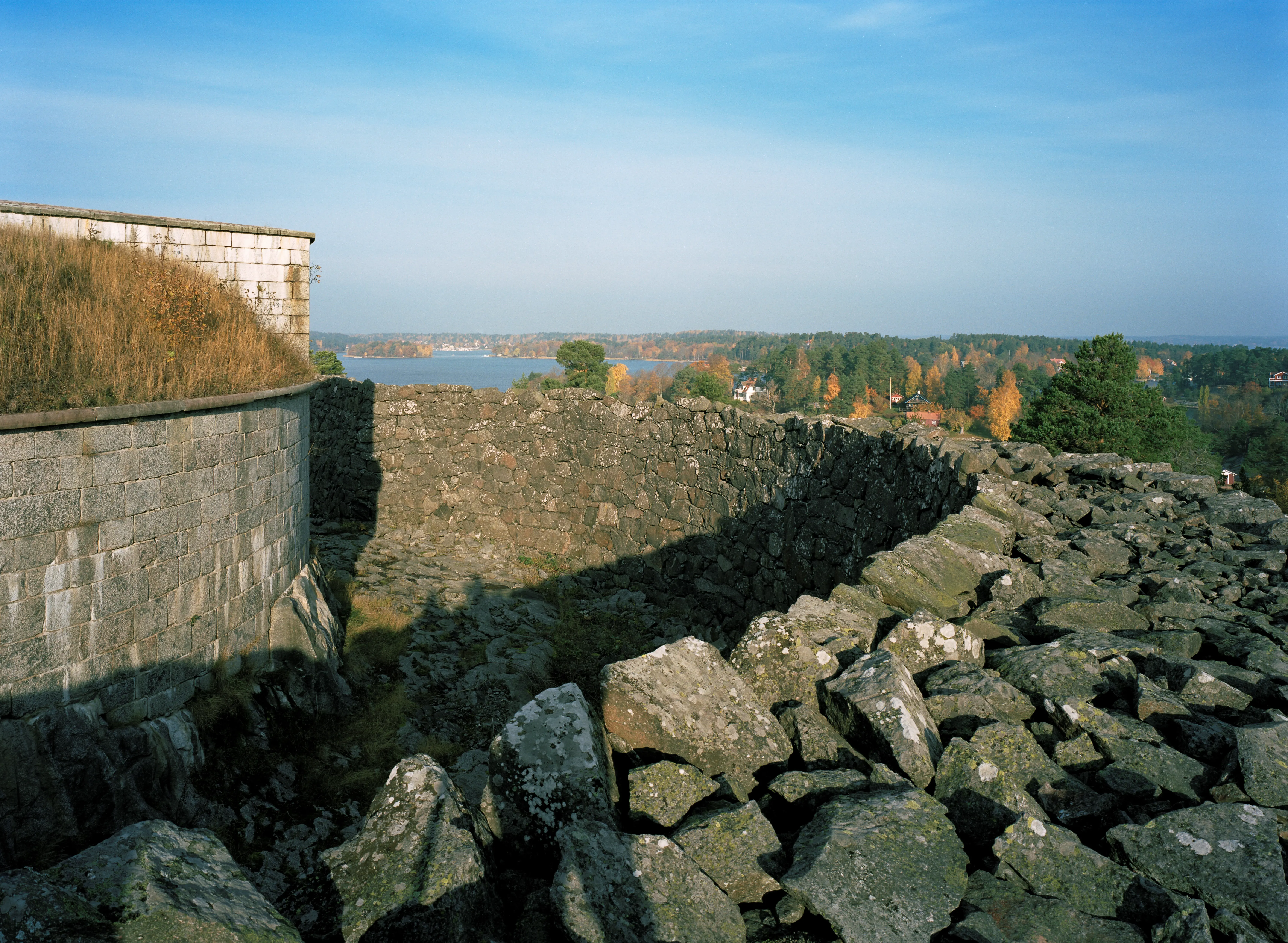 Utsikt från en rund stenvall på Rindö redutt. Vatten och höstfärger.