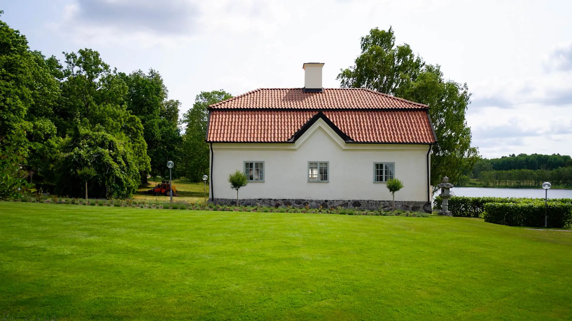 Vitt hus med grön gräsmatta i förgrunden en solig dag.
