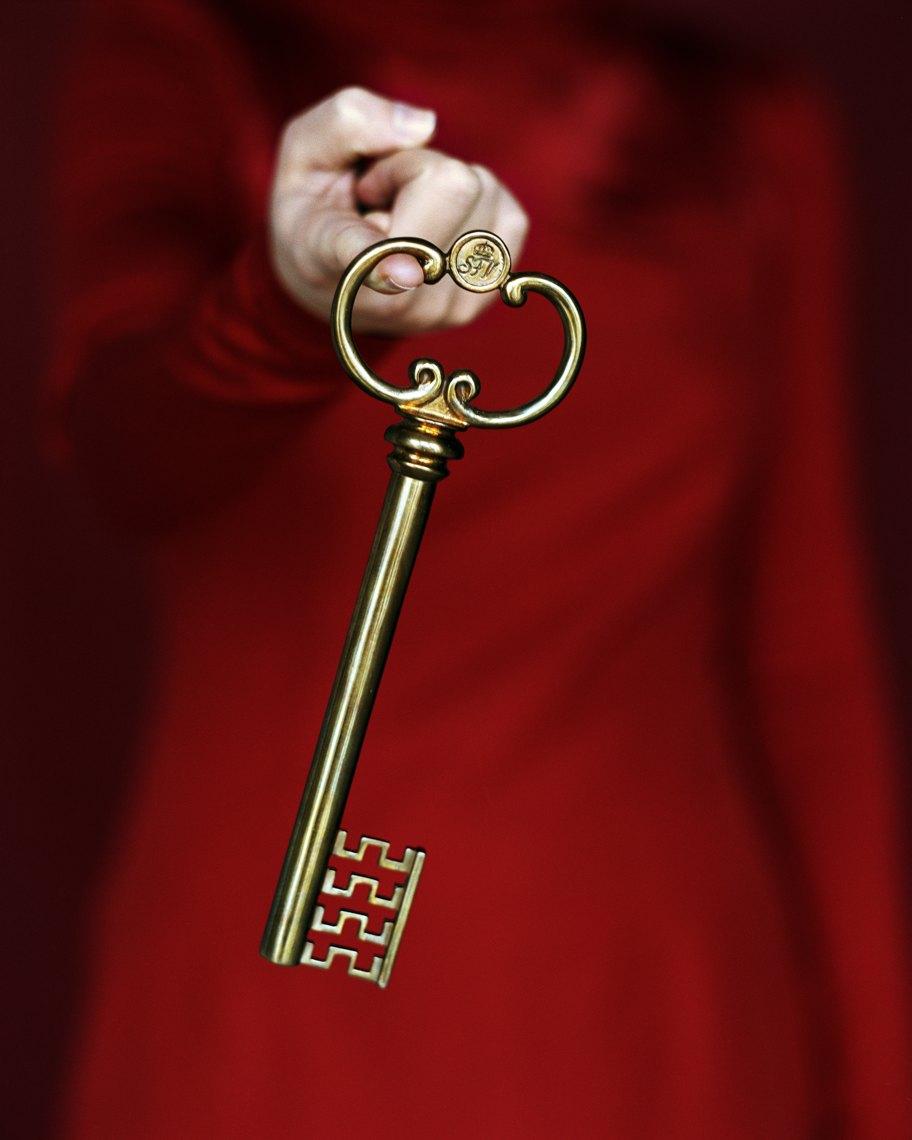 En person i röd klädsel håller hemliga rums nyckel i pekfingret.