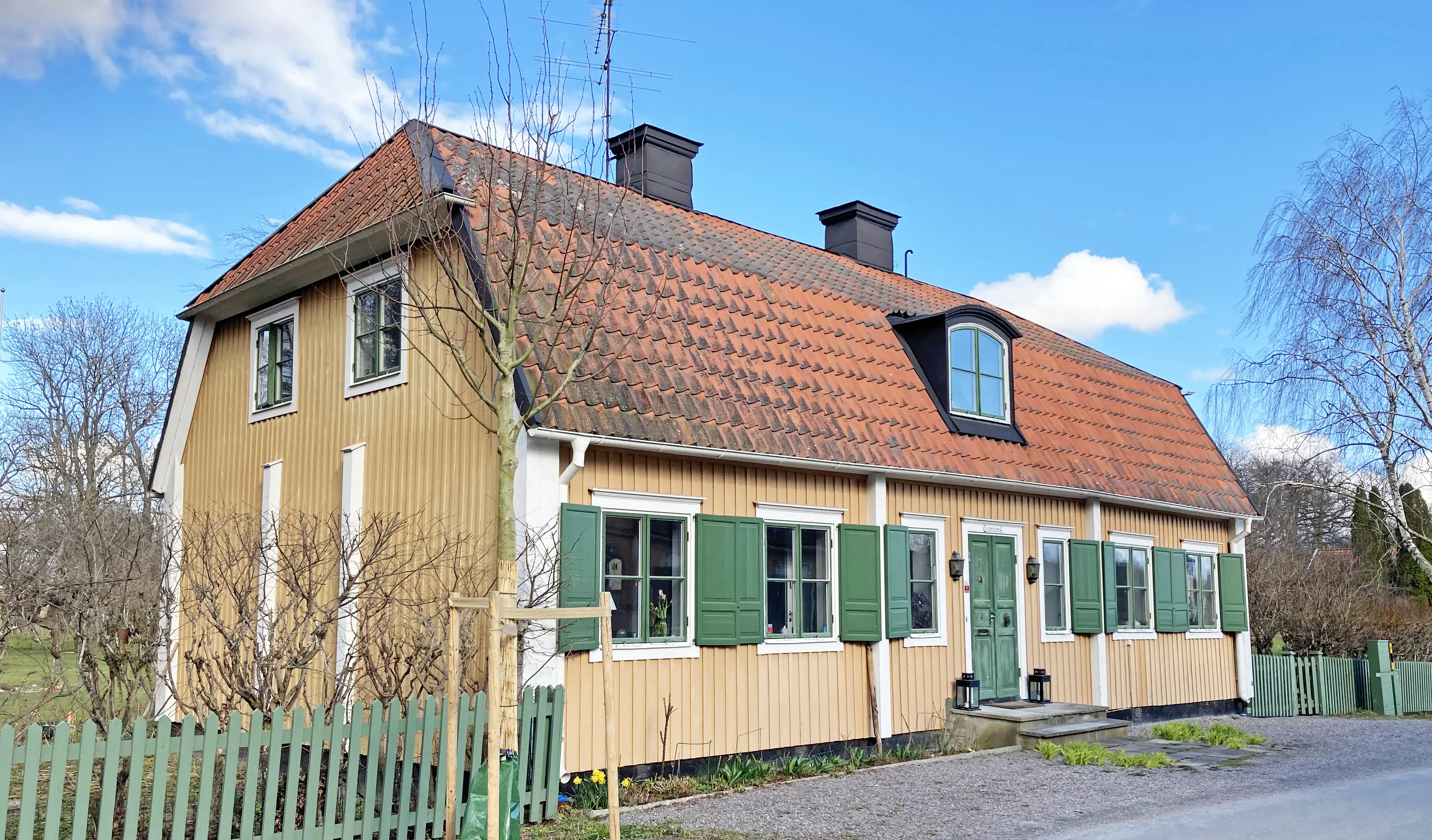 Kanton 4. Gult hus med gröna fönsterluckor. På tegeltaket sitter två skorstenar och en tak-kupa.