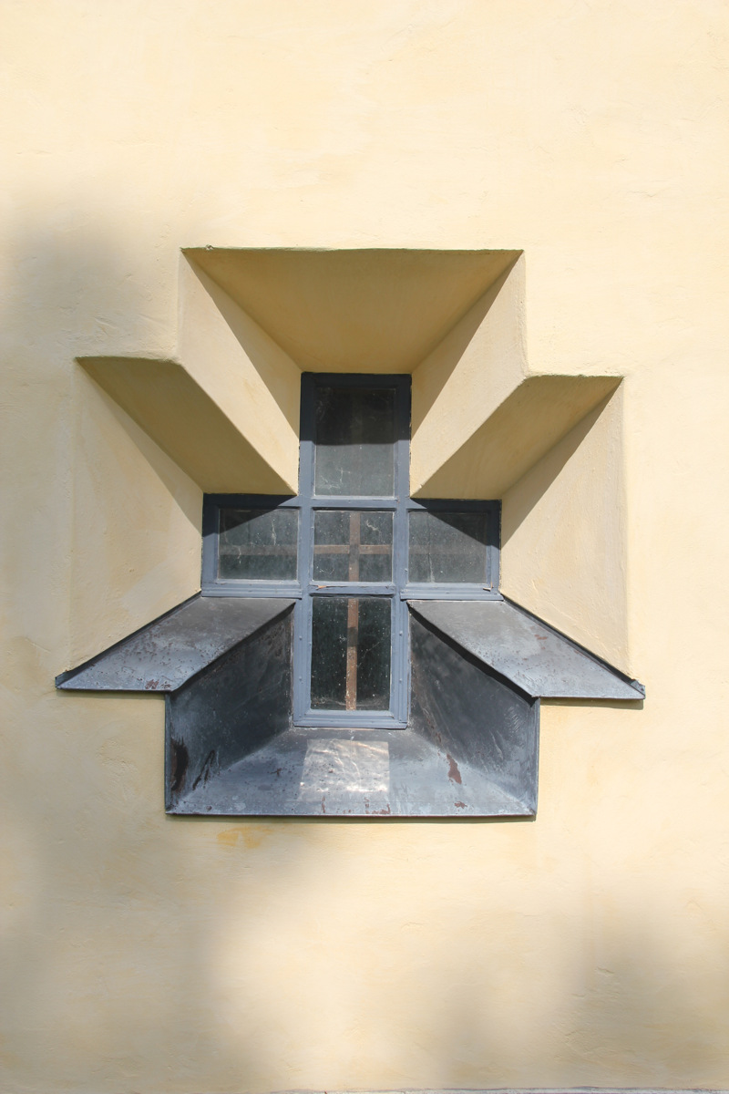 Roma kungsgård, fasad-detalj på huvudbyggnaden. Ett kors-format fönster insänkt i den tjocka, gulputsade väggen.