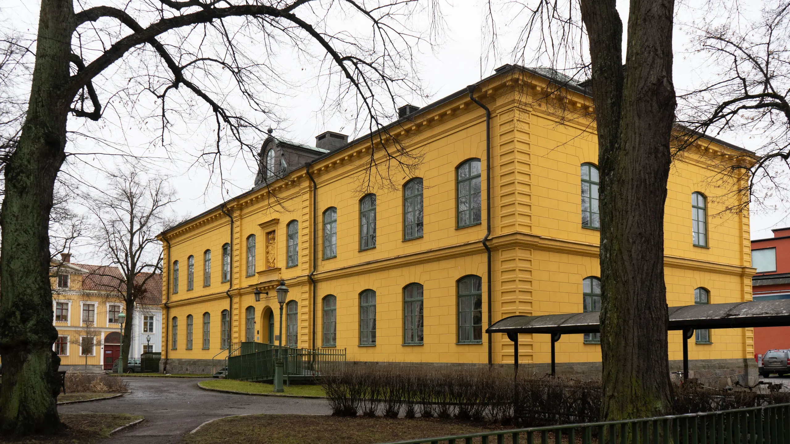 Ämbetsbyggnaden sedd utifrån, med nakna lövträd i förgrunden.