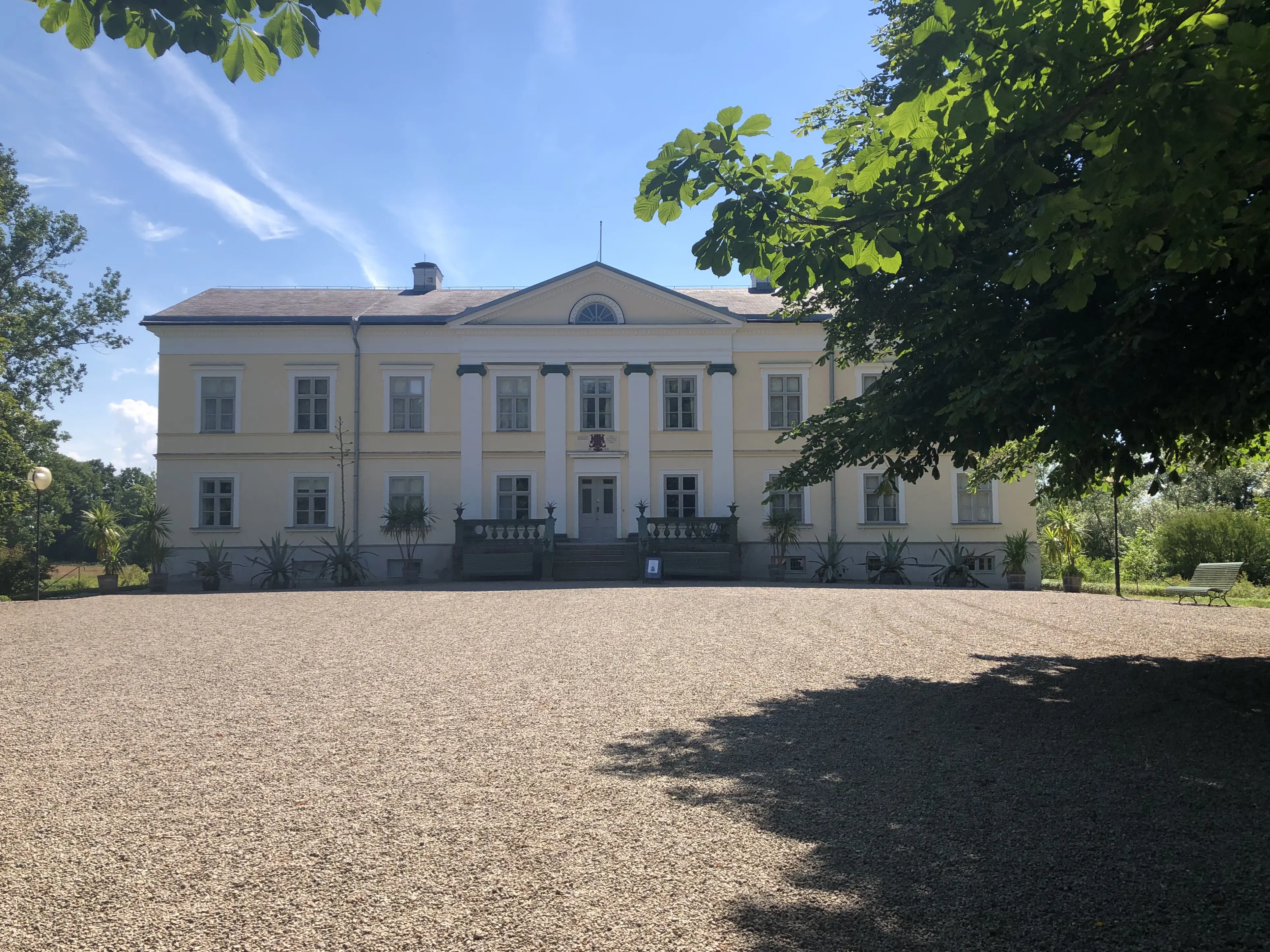 Huseby bruk. Herrgården, byggd i souterräng. Fasaden mot gårdsplanen har två våningar. Sommar och grönska.