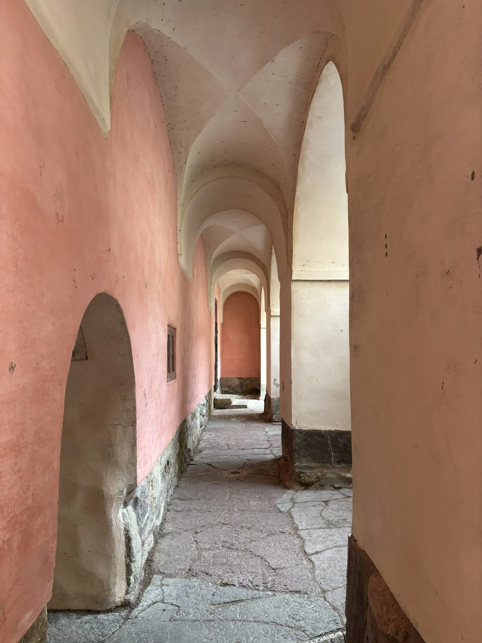 Korridor med valv och rosa putsade väggar.