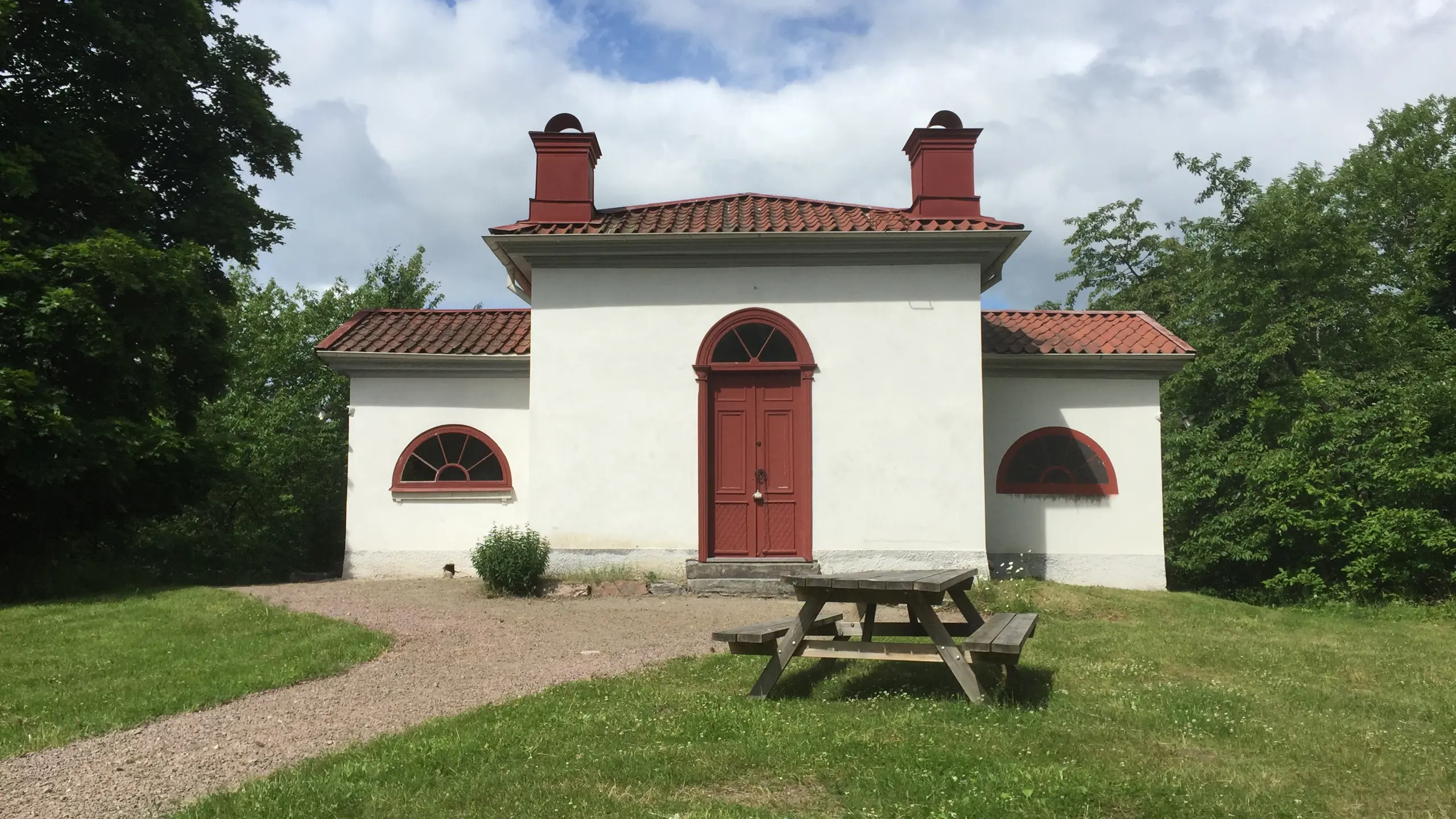 Vit byggnad med röd dörr och tegeltak