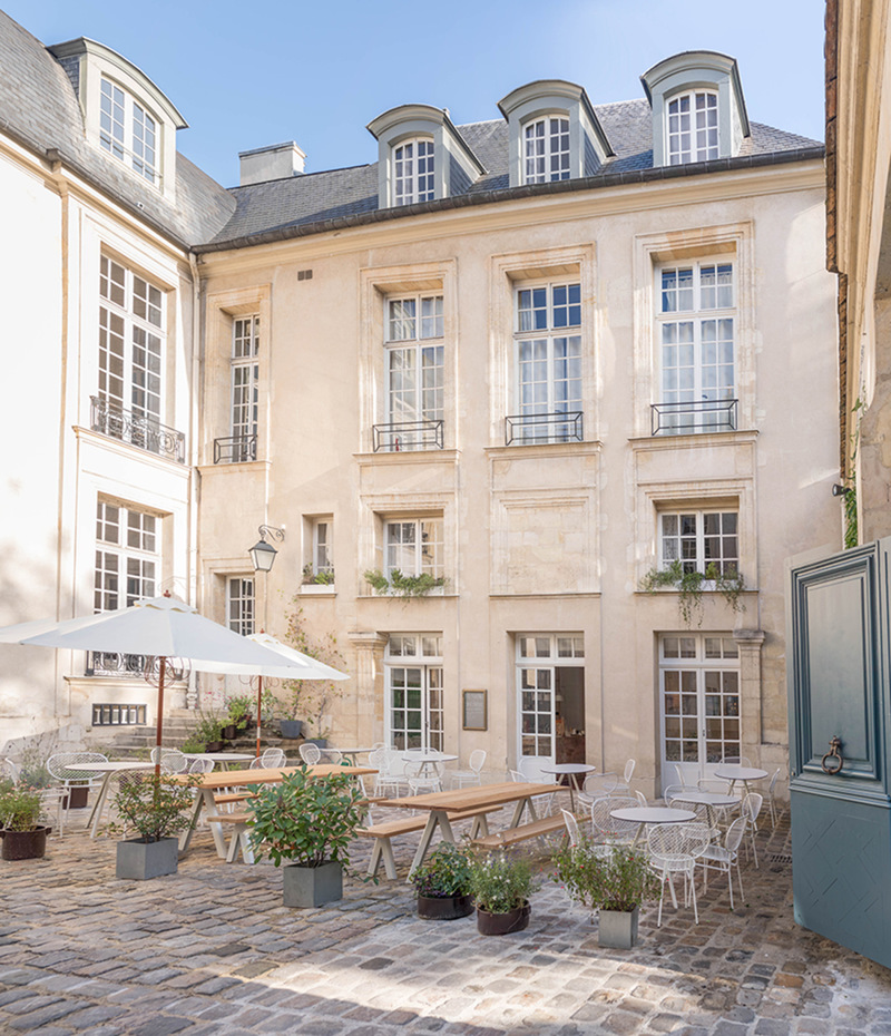 Svenska institutet i Paris. Den stenlagda innergården med uteservering ramas in av ljusa fasader med stora fönster. 