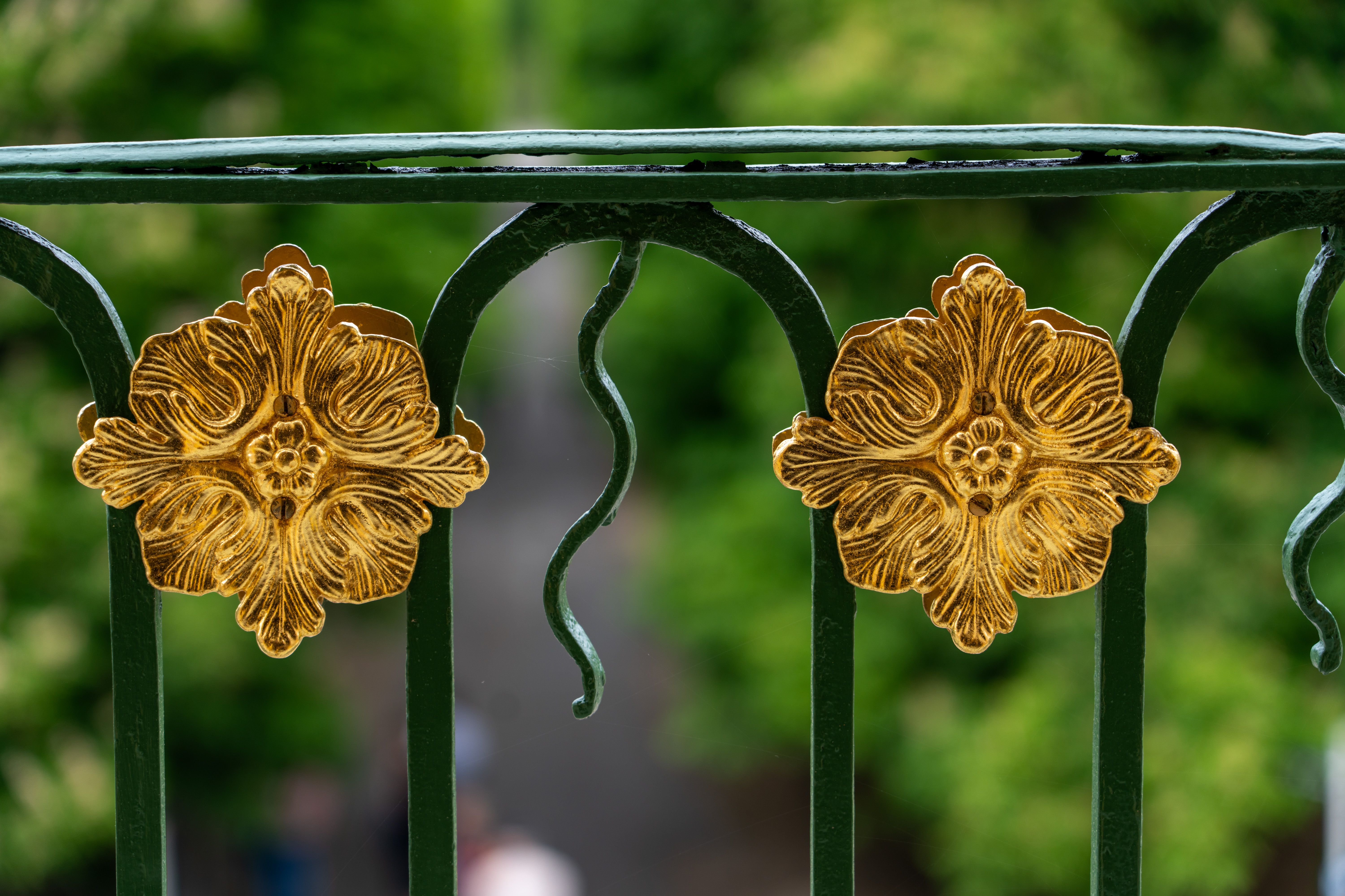 Förgyllda blommor på grönt trappräcke.