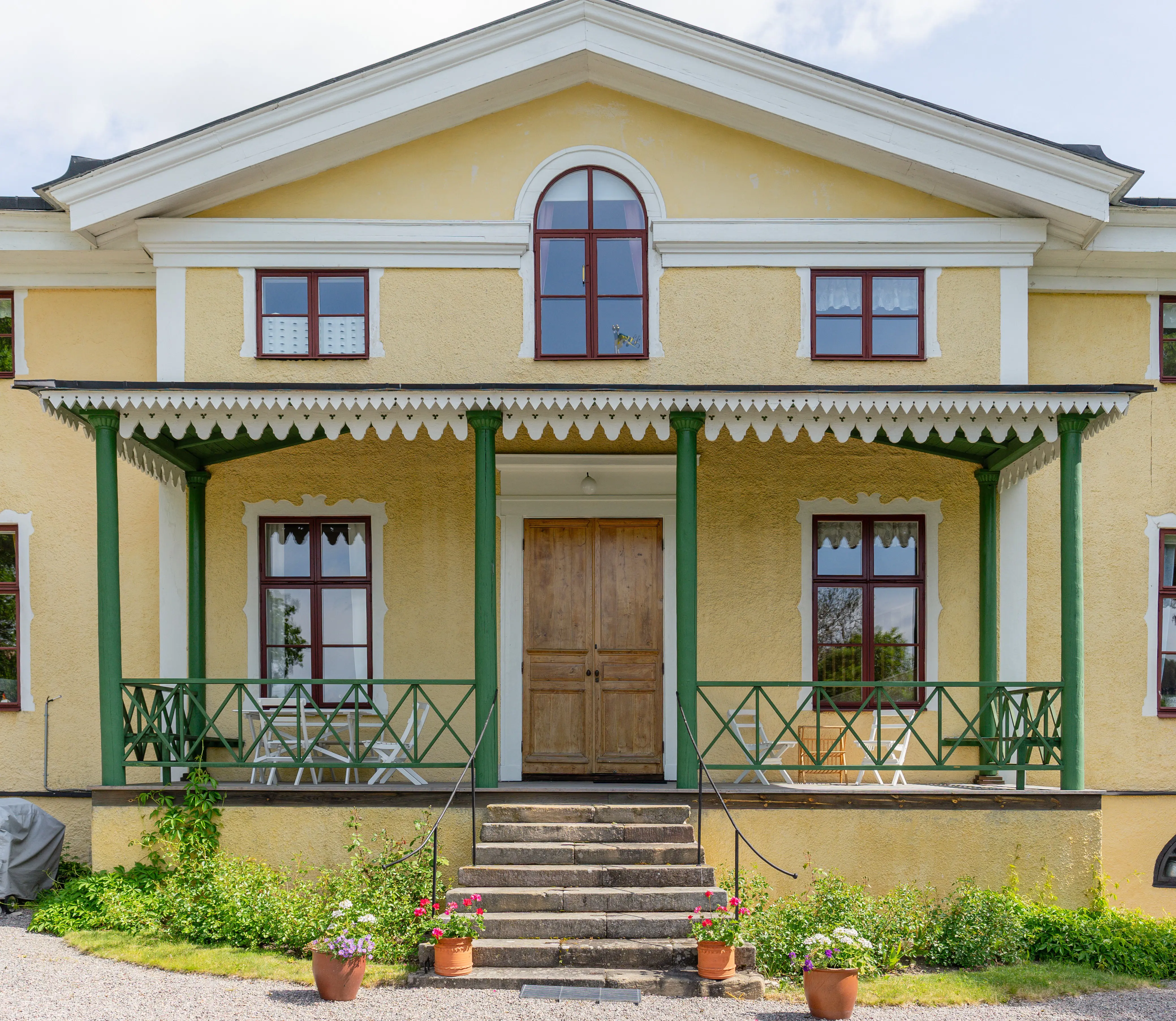Landsberga. Huvudbyggnaden, en gulputsad villa med stor entré-veranda.