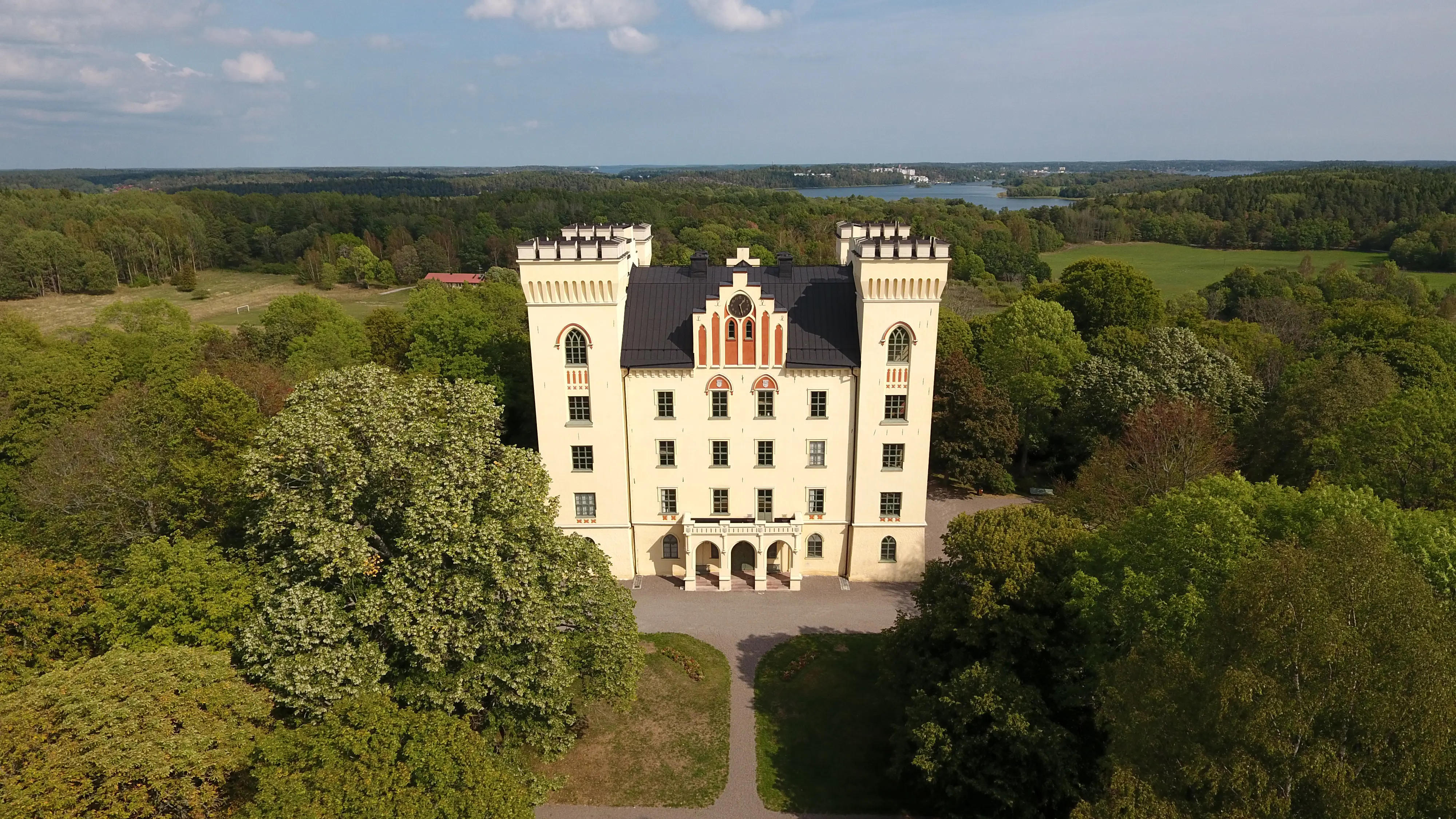Flygbild över Bogesunds slott och parkens lummiga trädkronor. I bakgrunden syns åkrar, hagar och Askrikefjärden.
