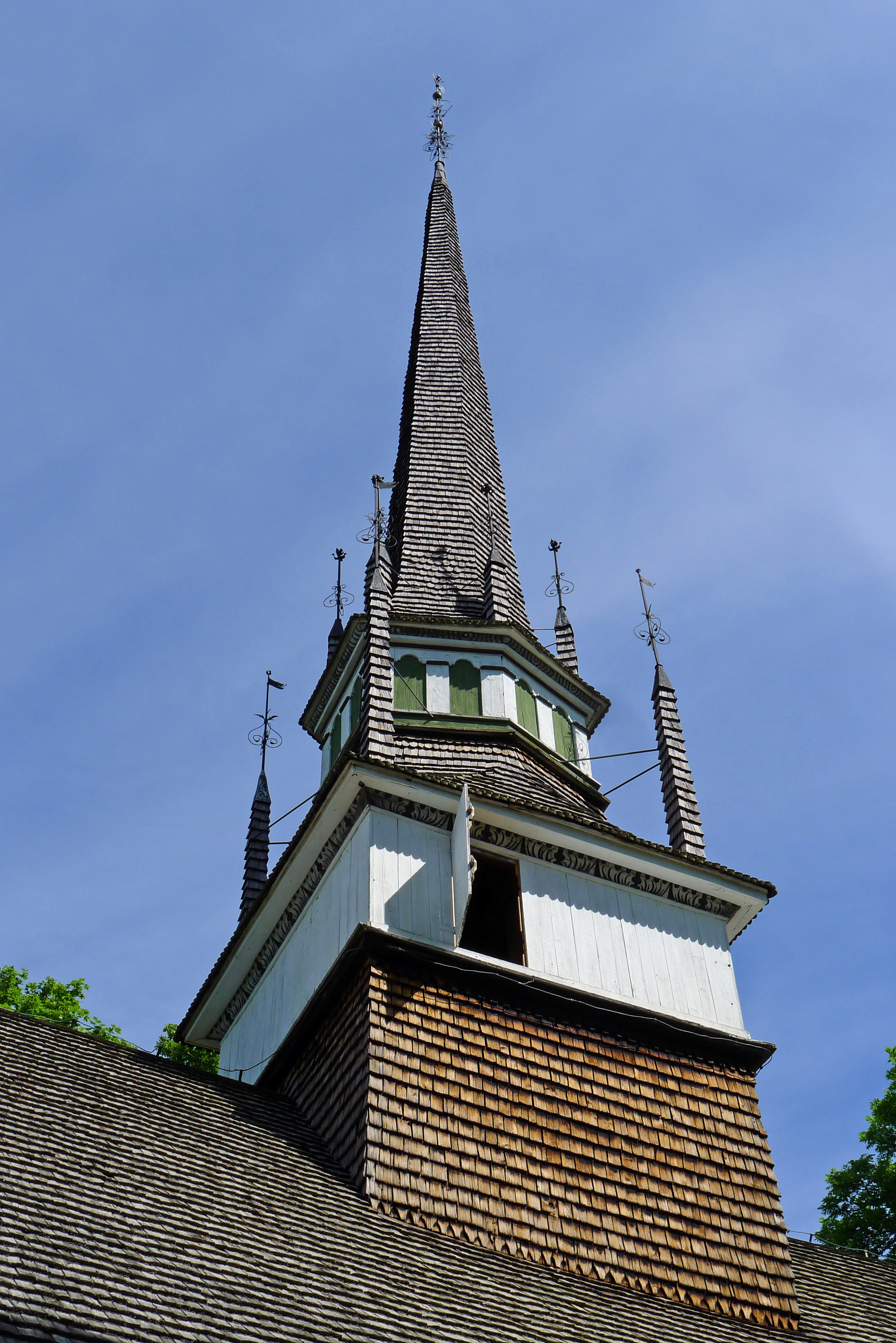 Brunneby kyrkas torn. Tornet är av trä, med flera sirliga spiror av smide. Både taket och tornet är spåntäckta.