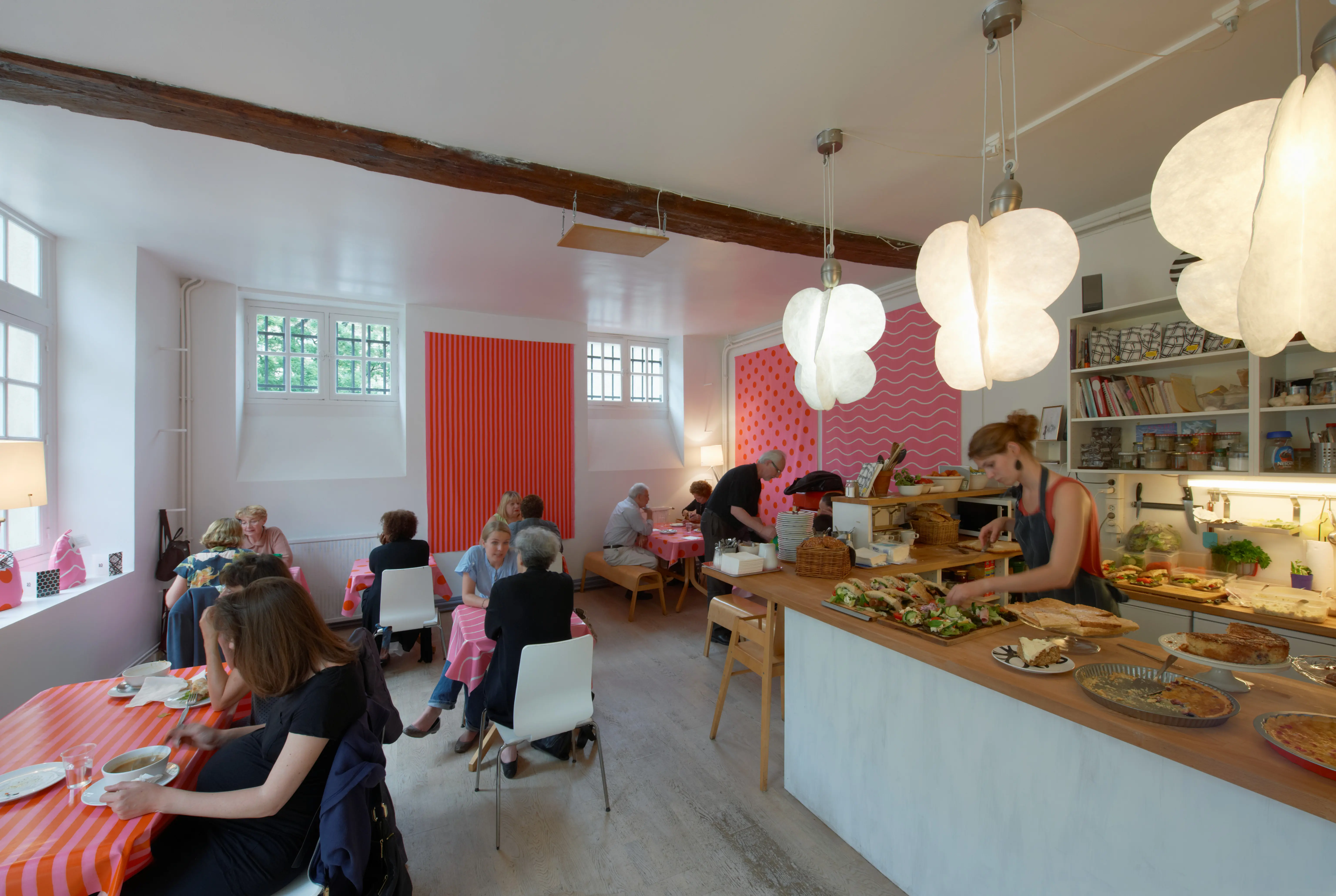 Svenska institutet i Paris. Café med ljus, enkel inredning och mönstrade röda färgfält på väggarna.