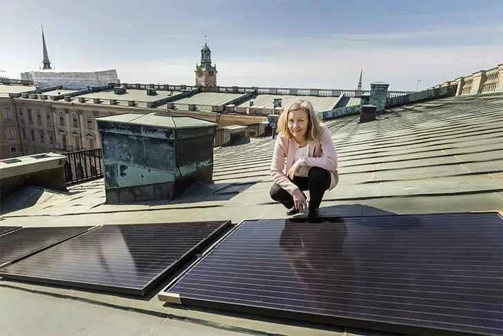 Fastighetschef Lotta Günther sitter vid solpanelerna på Stockholms slotts tak.
