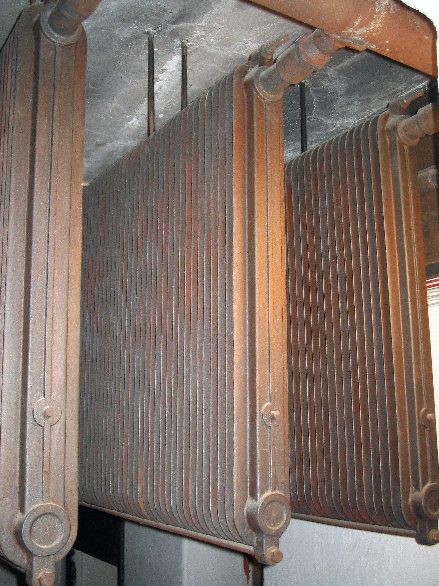 Tre stycken rödaktiga kalorifersystem fästa i taket.