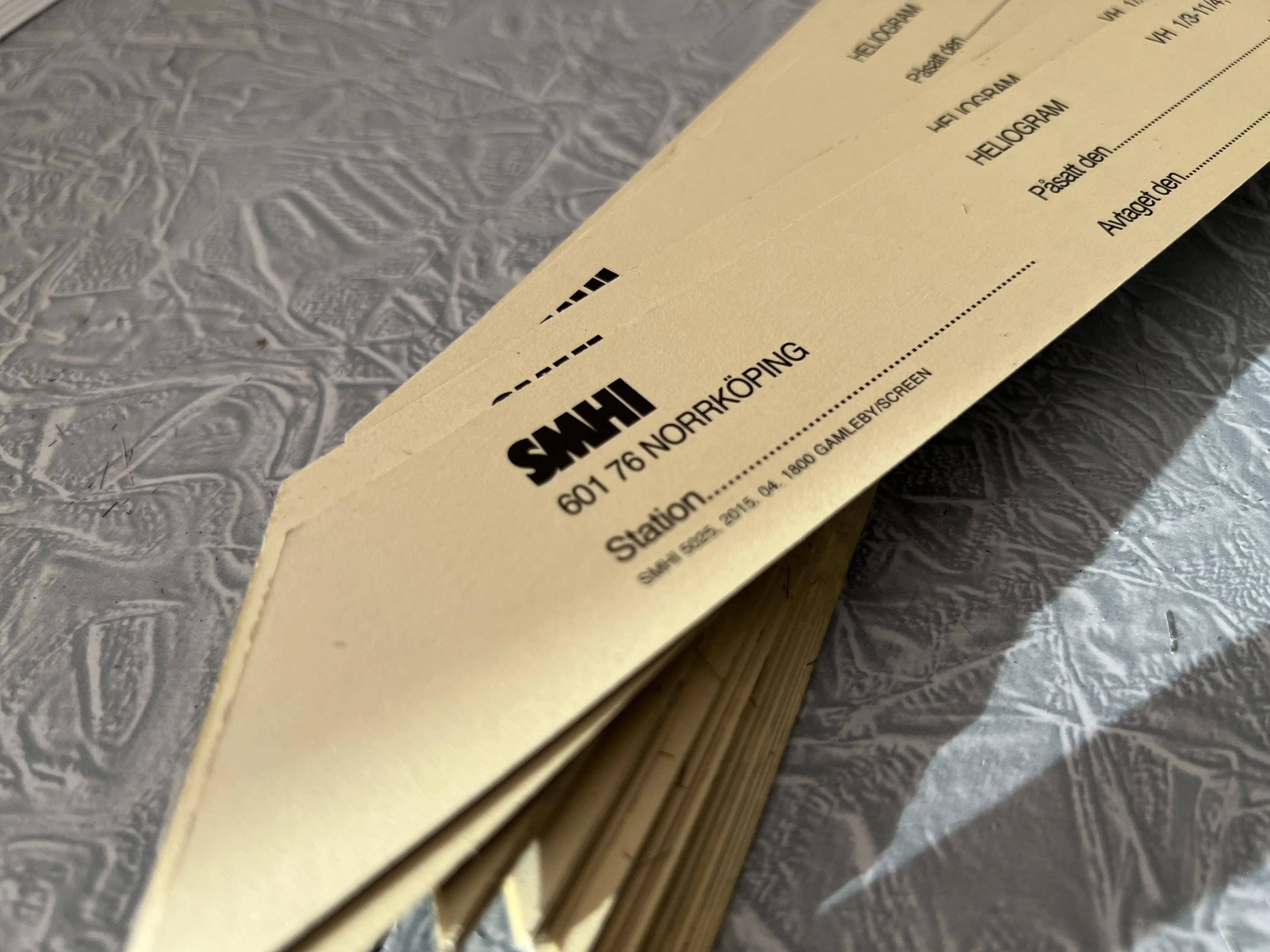 En hög med pappersremsor där det står SMHI, ligger på ett bord.