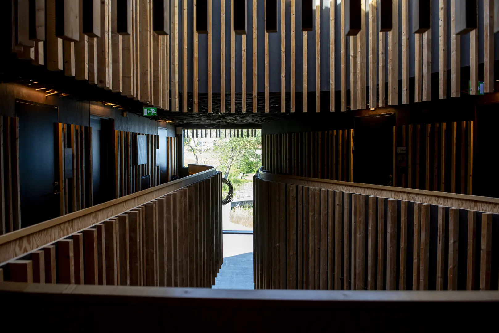 Naturum Vänerskärgården, interör. Perspektiv genom atriet med gles, stående träpanel.