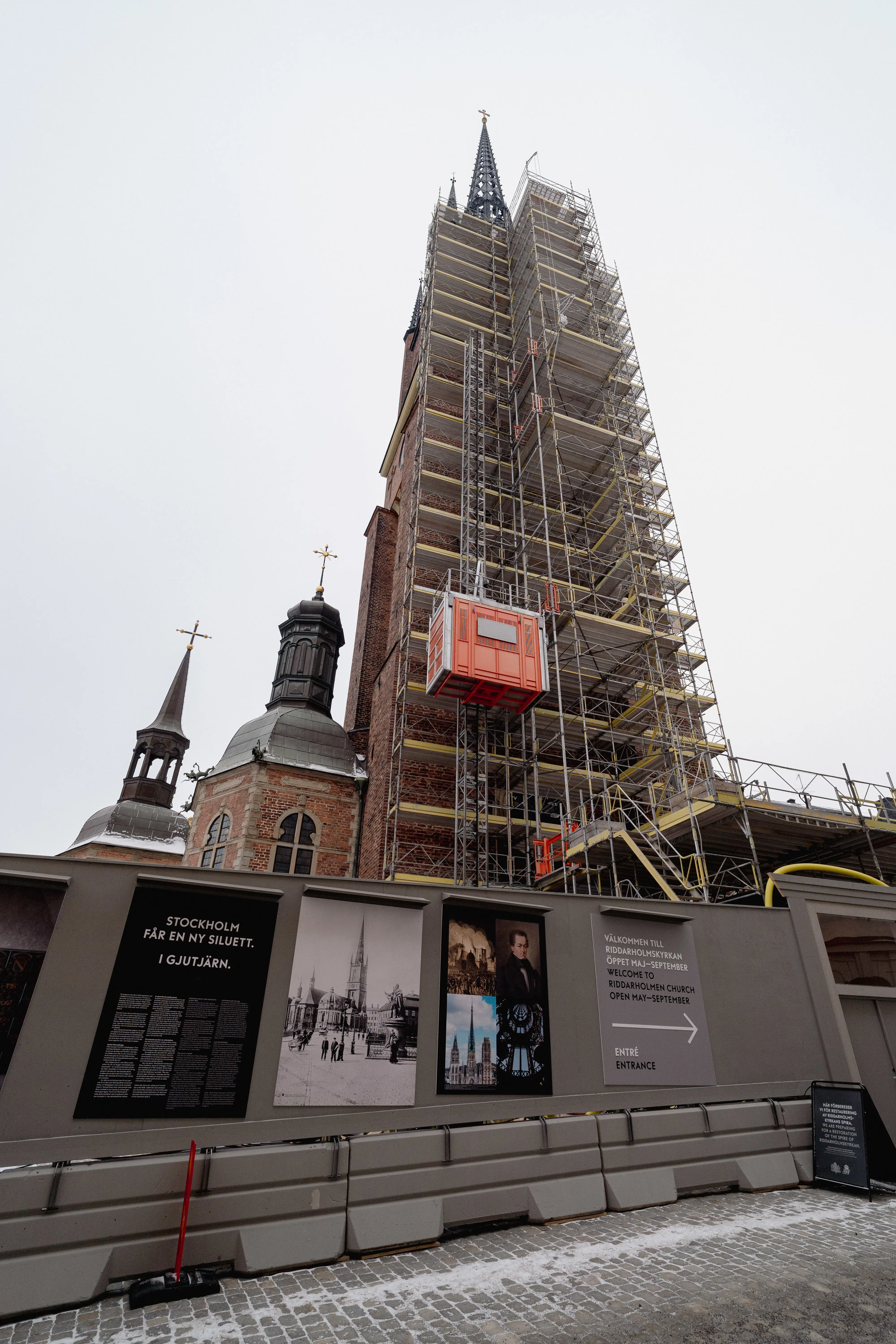 Riddarholmskyrkan. Byggställningar är resta längs tornet, innanför bygg-plank med information om projektet.